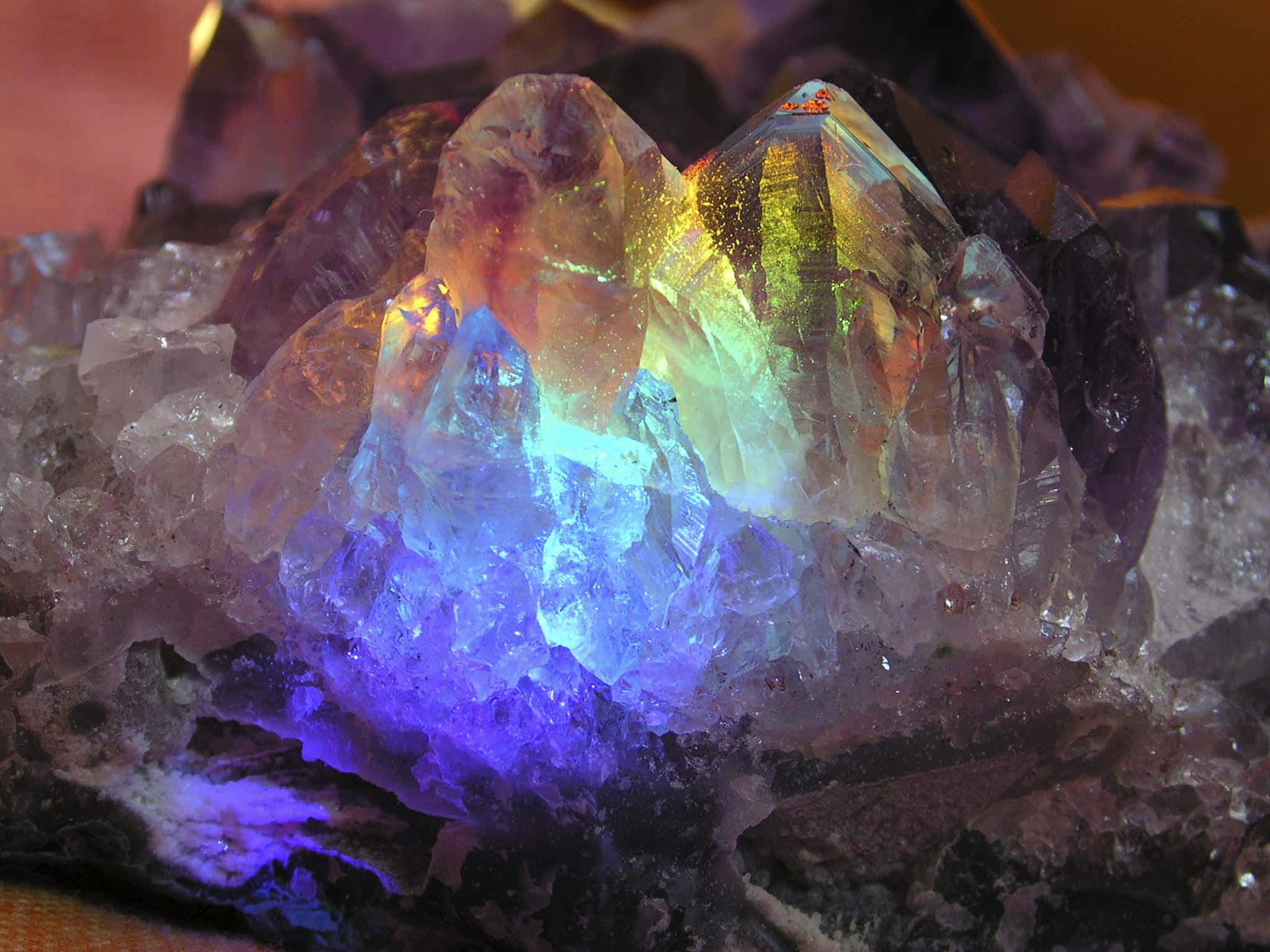 Amethyst 桌布 壁紙 — 一簇紫水晶晶體，在戲劇性的燈光下閃耀著鮮豔的藍色、紫色和彩虹色調。