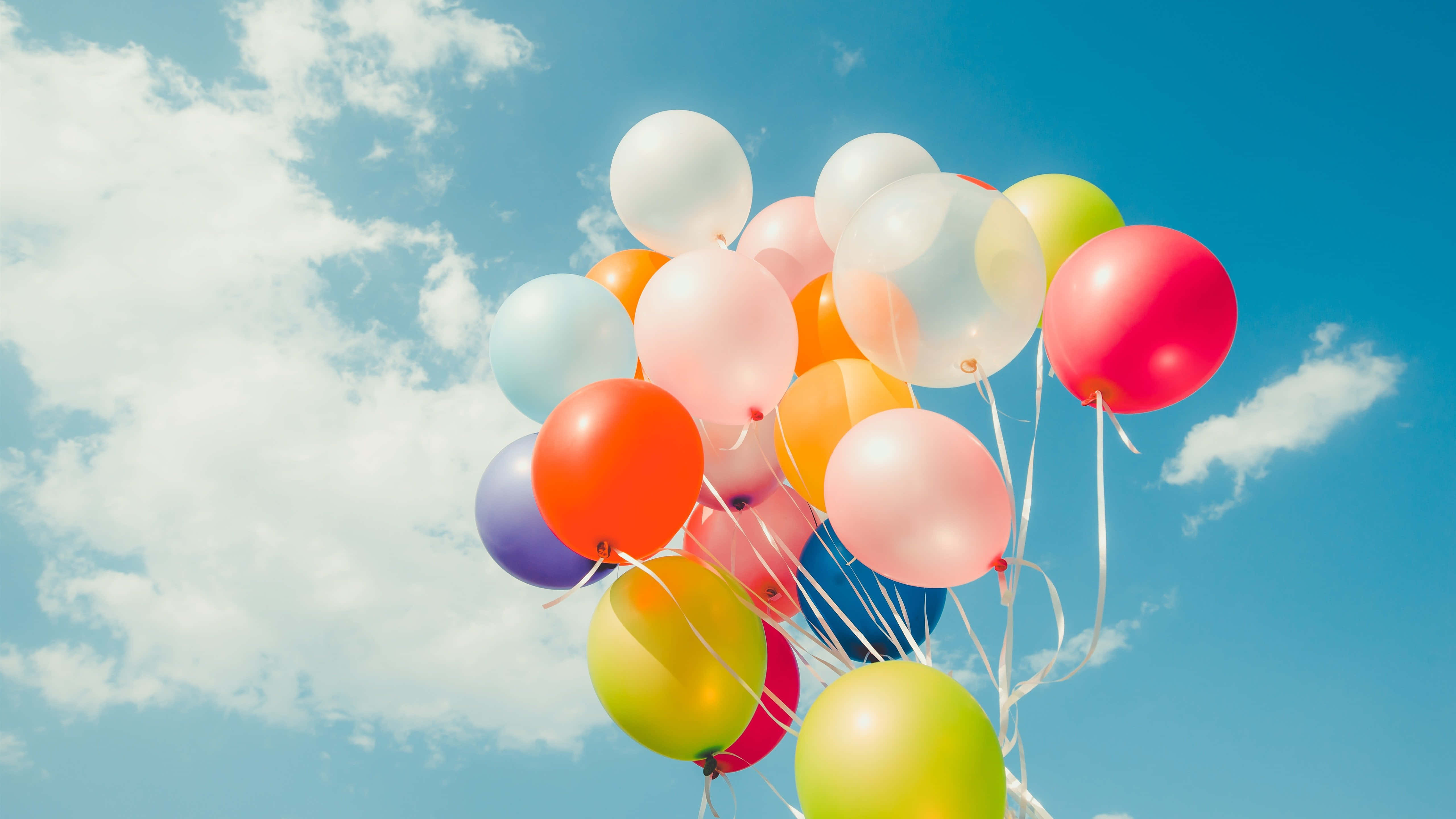 Balloon 桌布 壁紙 — 一簇色彩繽紛的氣球在晴朗的藍天中飄浮，伴隨著蓬鬆的白雲。