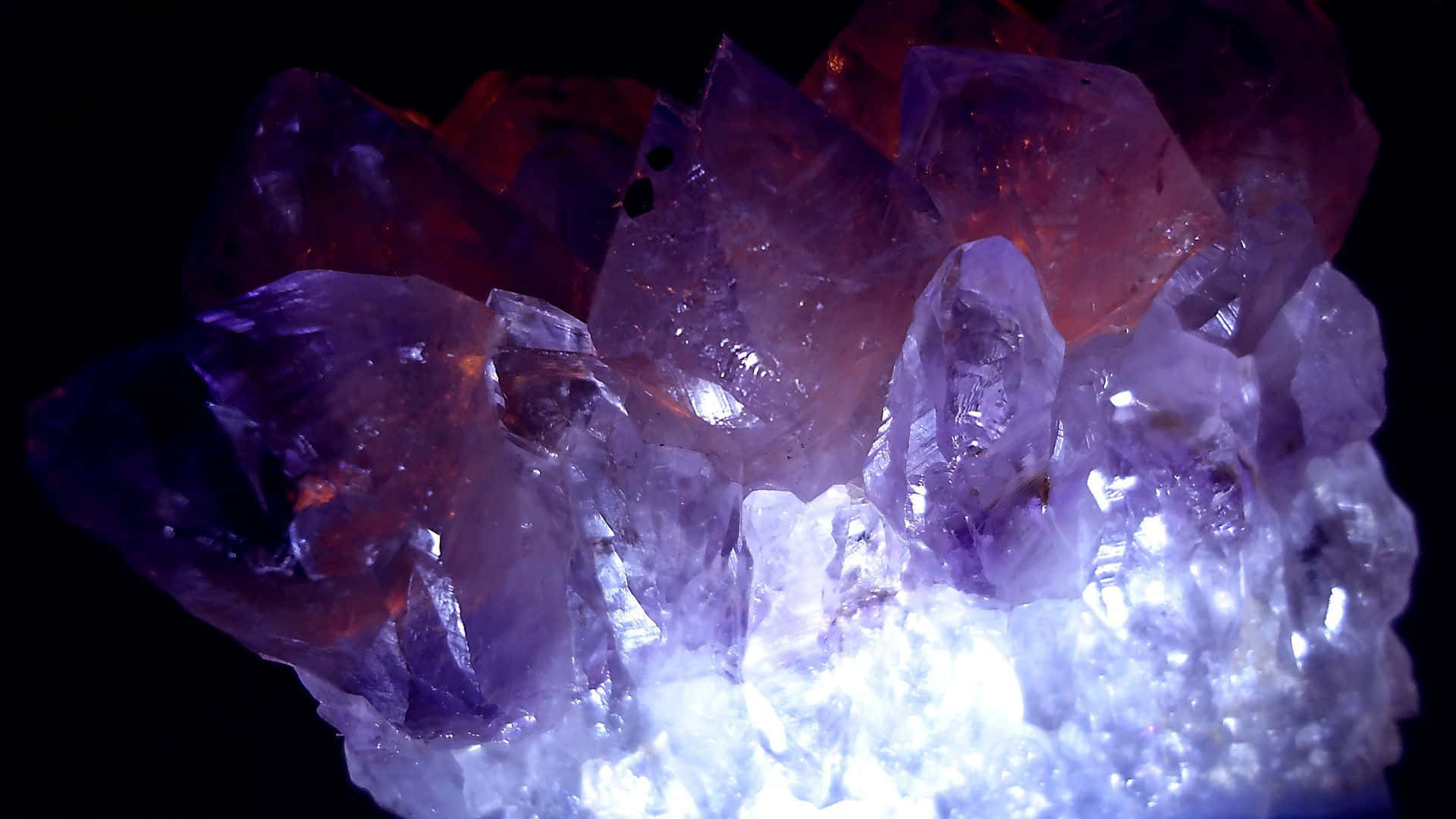 Amethyst 桌布 壁紙 — 一簇閃耀的紫水晶在純黑背景下散發著充滿活力的紫色和白色光芒。