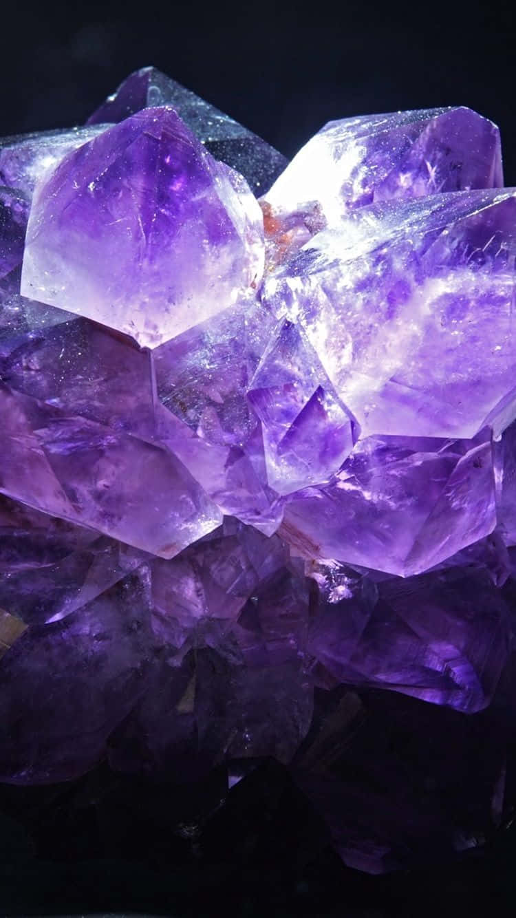 Amethyst 桌布 壁紙 — 一簇閃耀的紫色紫水晶晶體在聚焦光線下，在深黑色背景上閃閃發光。