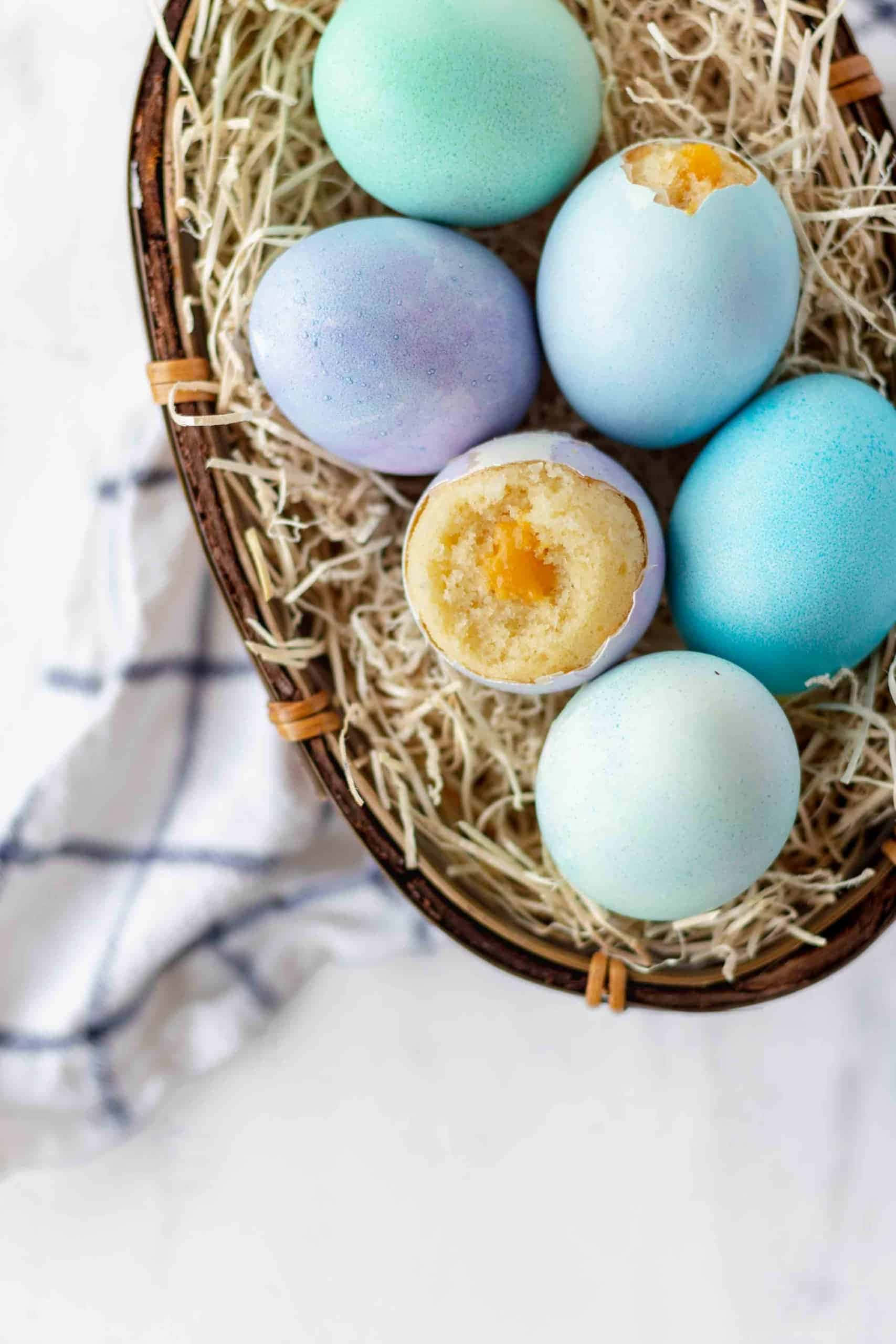 Eggshell 桌布 壁紙 — 一籃粉藍色雞蛋放在稻草中，兩隻裂開露出金黃色蛋黃。
