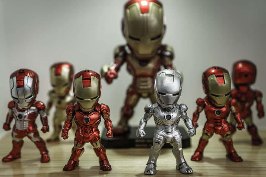 Iron Man Action Figures 桌布 壁紙 — 一系列身穿紅色、金色和銀色裝甲的鐵甲奇俠動作人偶在木質表面上擺出姿勢。