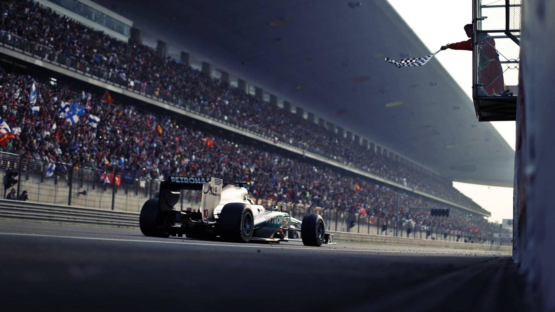 F1賽車越過終點線，工作人員揮舞方格旗。