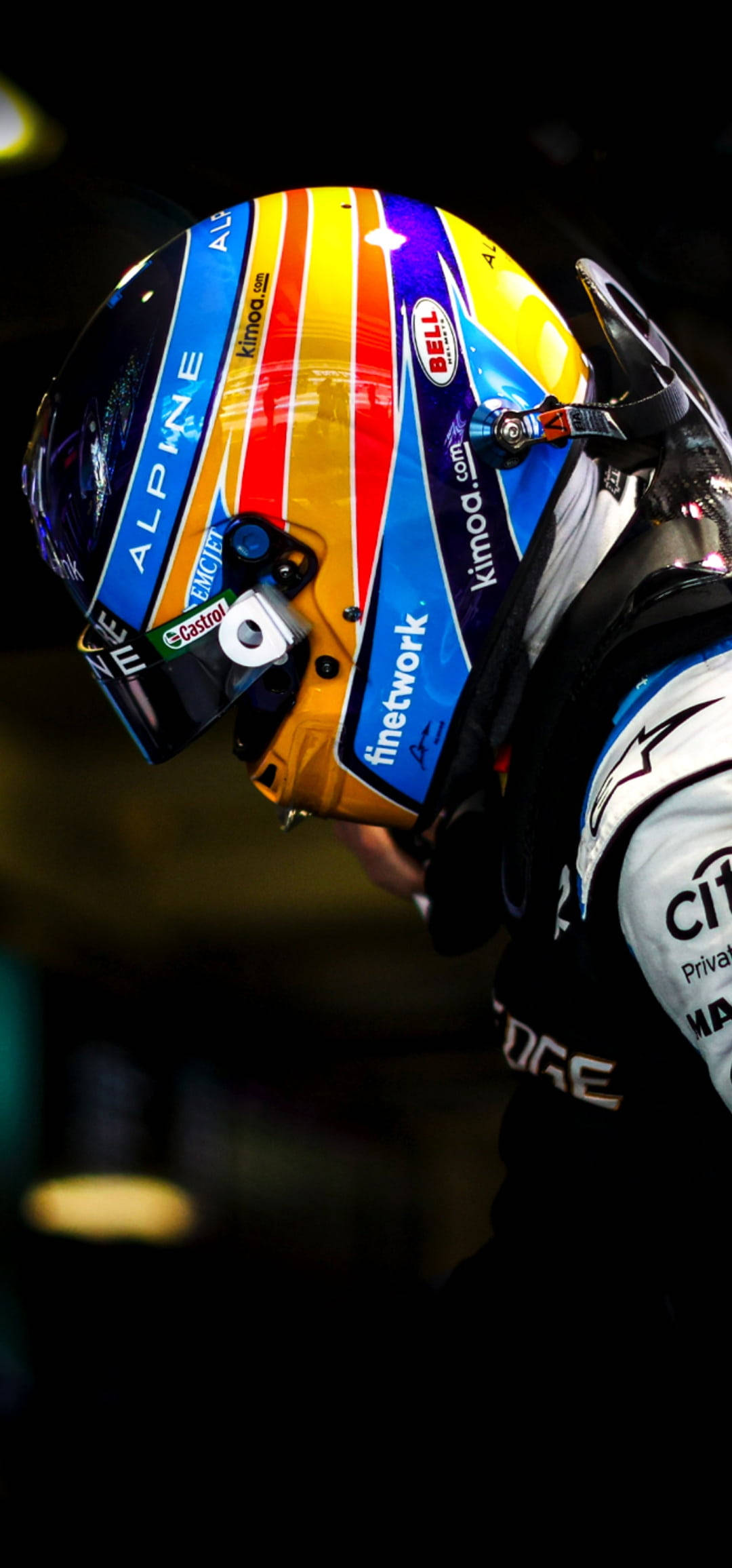 Fernando Alonso 桌布 壁紙 — 一級方程式賽車手色彩繽紛的頭盔特寫，帶有贊助商標誌，在戲劇性燈光下。