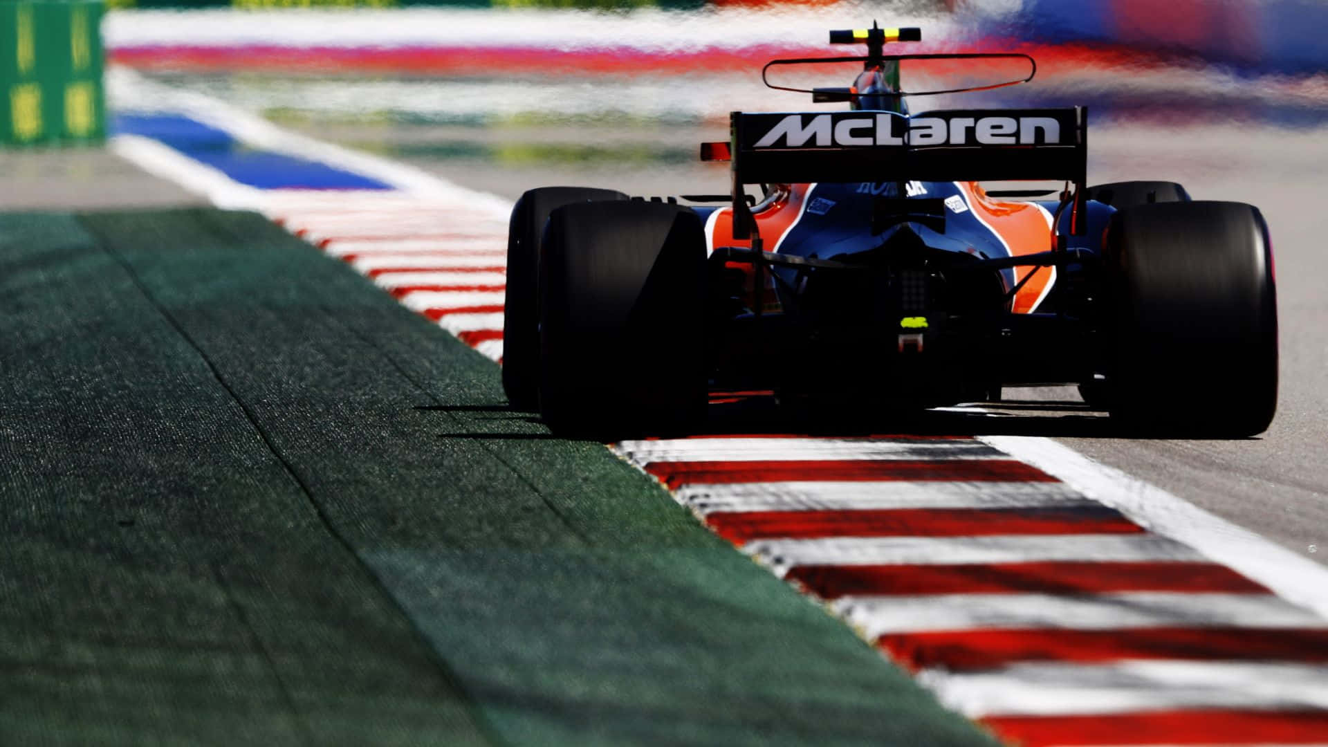 麥拿倫F1賽車在設有紅、白、綠色路緣石的賽道上疾馳。