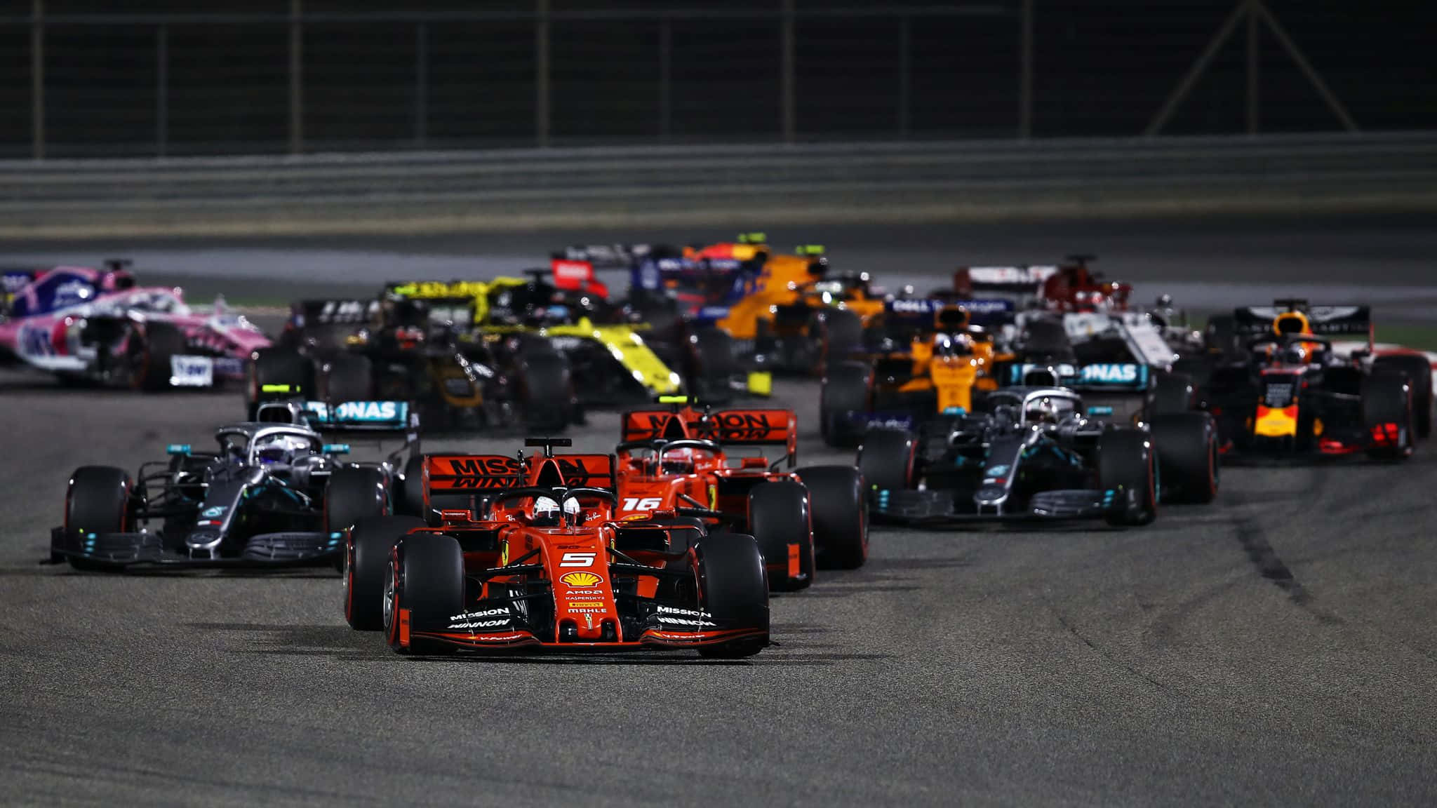 F1 2019 桌布 壁紙 — 一級方程式賽車車群在夜間於賽道上，在明亮的泛光燈下緊密競賽。