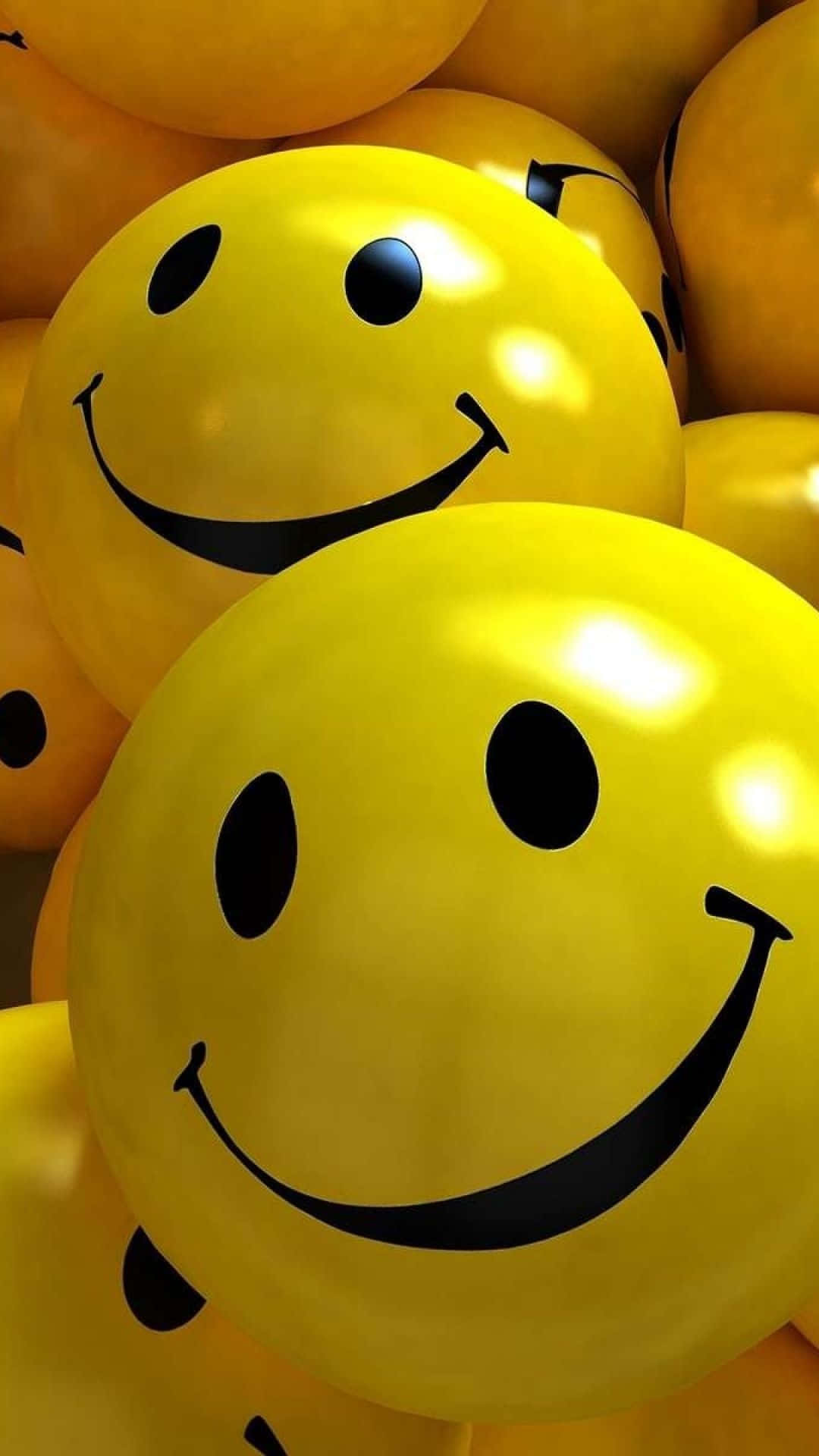 Animojis 桌布 壁紙 — 一組帶有簡單黑色笑臉的光澤黃色氣球的近距離特寫。