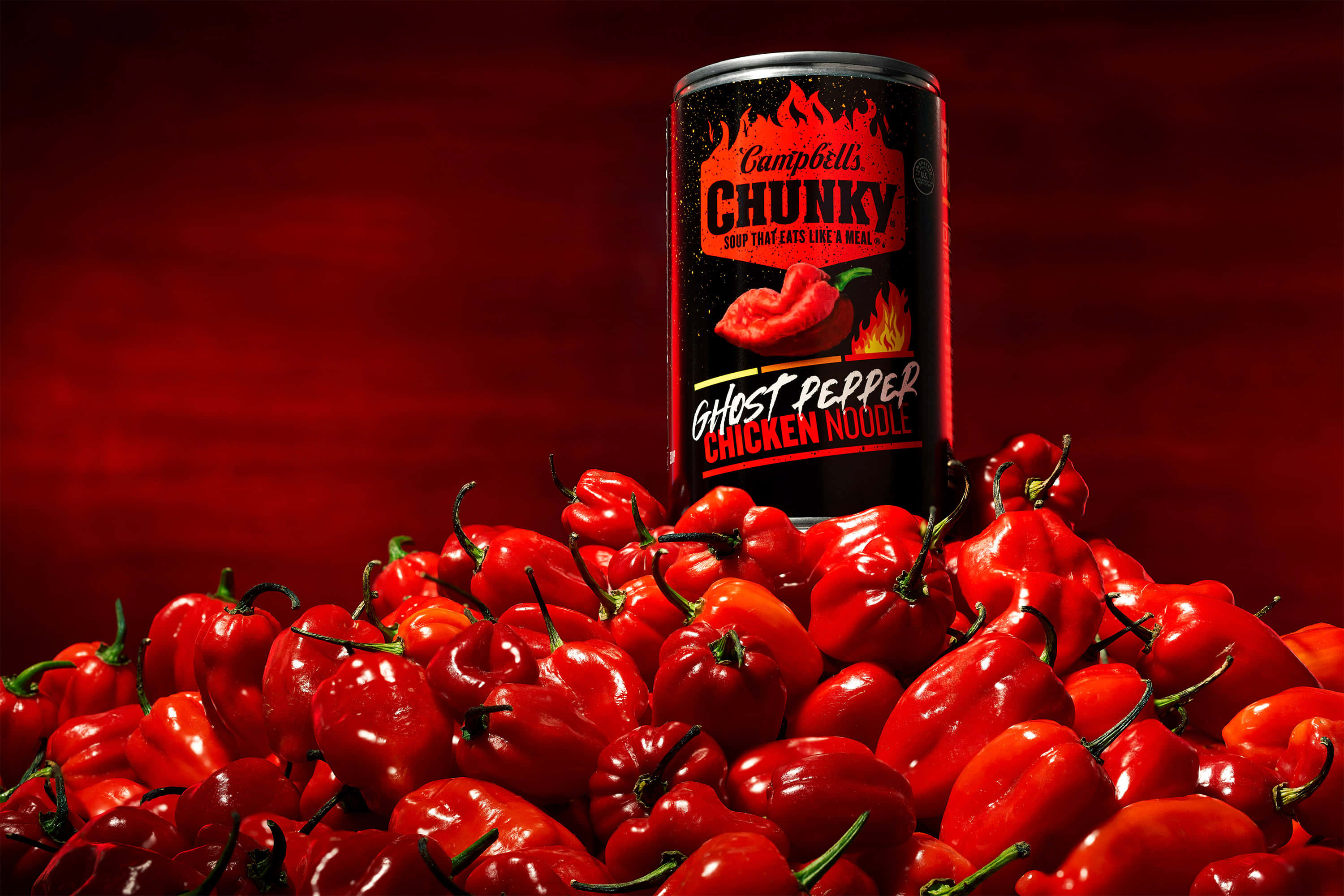 Ghost Pepper 桌布 壁紙 — 一罐Campbell's Chunky Ghost Pepper Chicken Noodle湯罐頭放在一堆鮮紅色的辣椒上，背景是深紅色的。