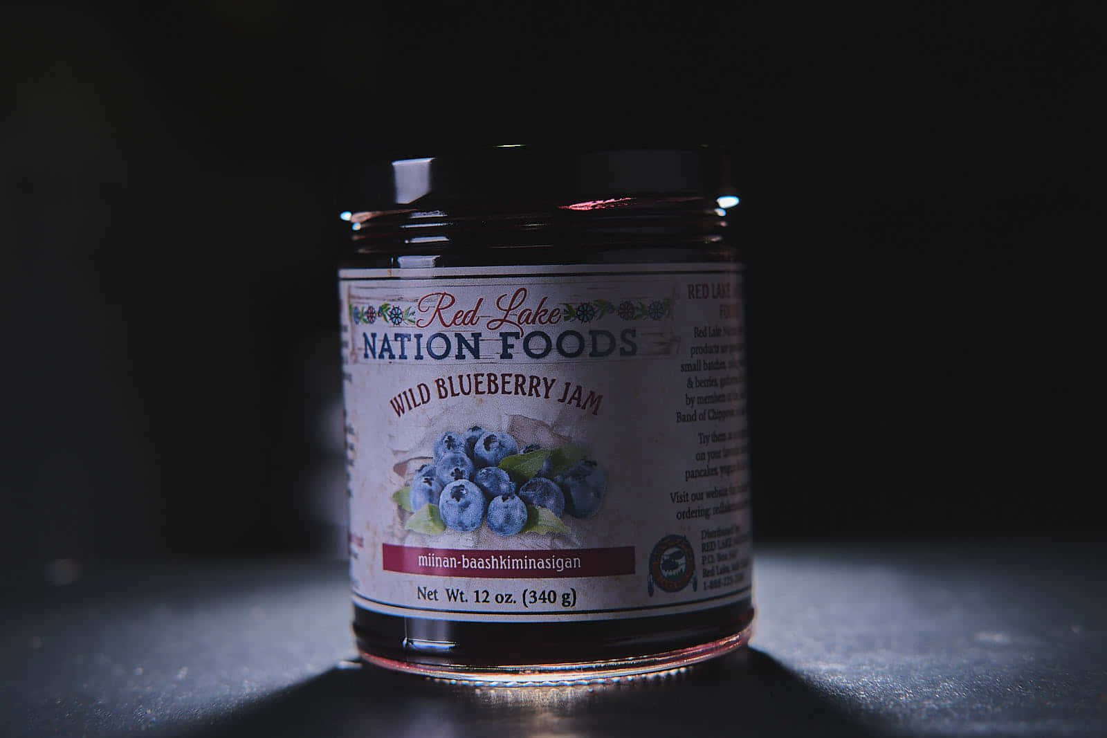 Blueberry Jam 桌布 壁紙 — 一罐來自 Red Lake Nation Foods 的野生藍莓果醬，在深色背景的襯托下，呈現出戲劇性的光影效果。