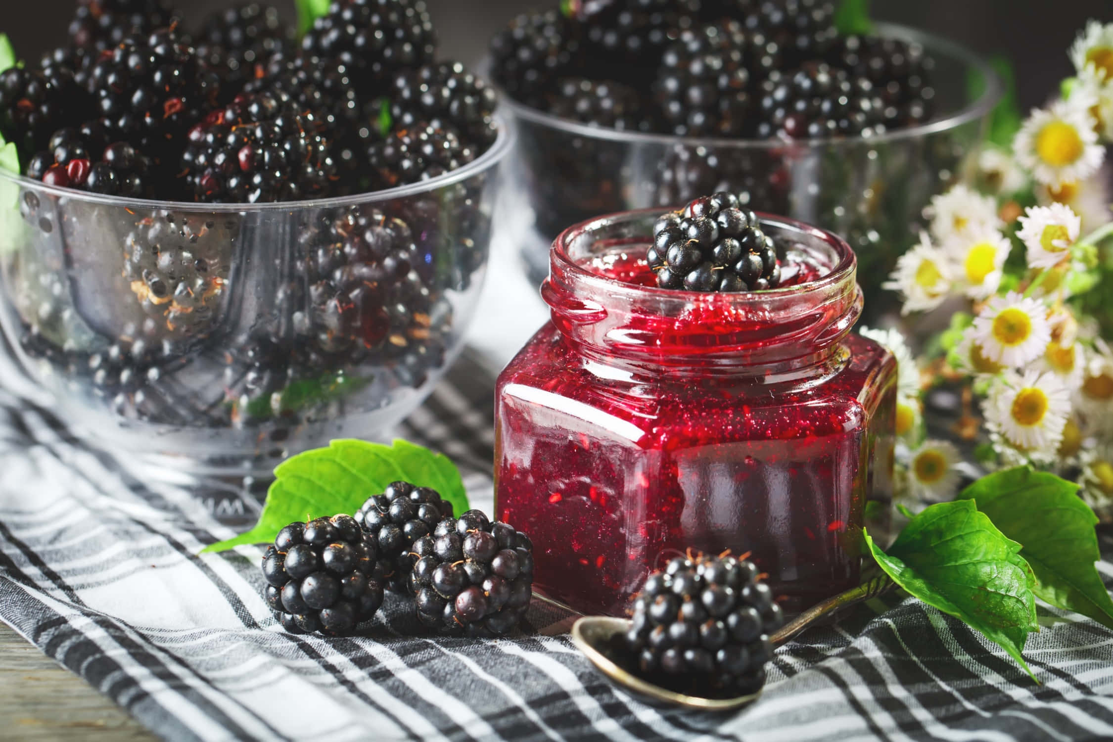 Blackberry Jam 桌布 壁紙 — 一罐光澤的黑莓果醬放在條紋布上，旁邊有新鮮莓果和雛菊。