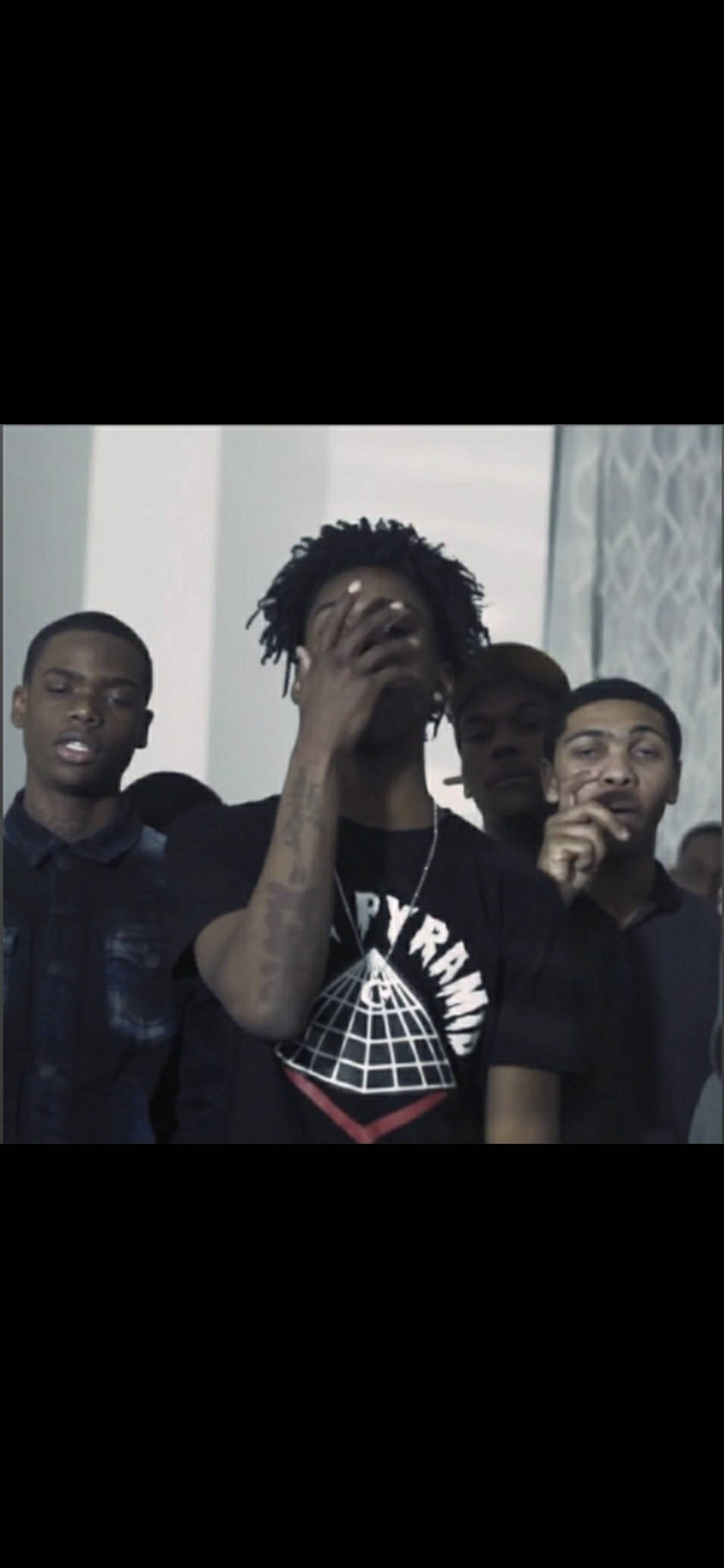 Polo G《Neva Cared》 壁紙 — 一群年輕男性在光線昏暗的室內空間，一人用手遮住臉，其他人在旁觀看。