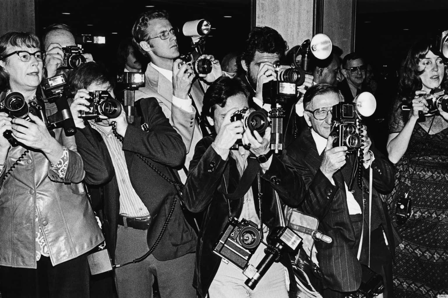 Paparazzi 桌布 壁紙 — 一群攝影師在新聞發布室內，將帶有閃光燈的復古相機對準一個看不見的主體。