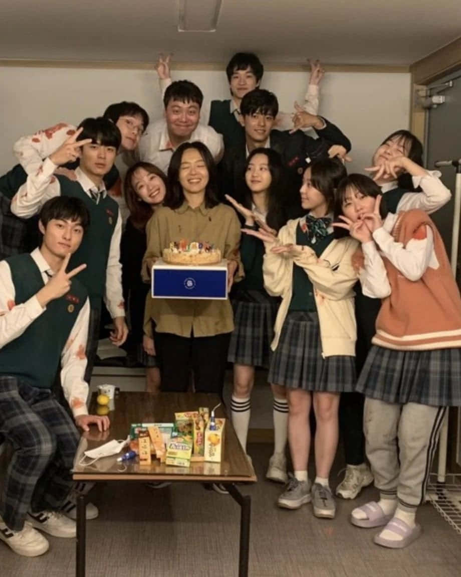 我哋都係死人 桌布 壁紙 — 一群穿著校服的青少年在舒適的室內房間裡圍著生日蛋糕愉快地擺姿勢。