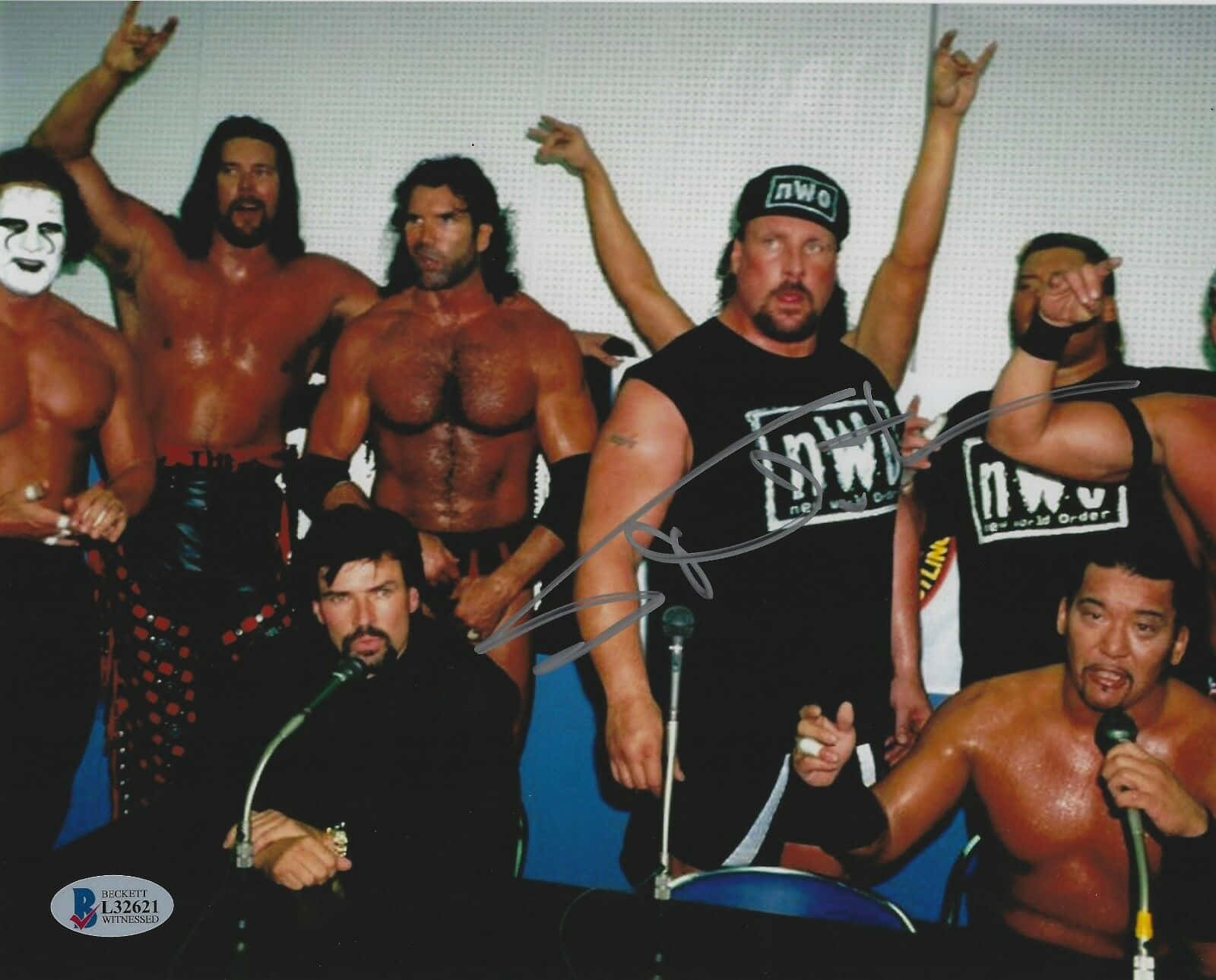 Scott Norton World Championship Wrestler 壁紙 — 一群肌肉發達的摔角手身穿nwo裝備，在記者會上自信地擺姿勢，手持麥克風並舉起拳頭。