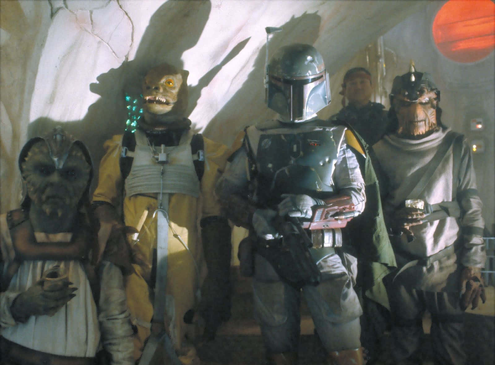 Bounty Hunters 桌布 壁紙 — 一群身穿盔甲和長袍的外星賞金獵人站在光線昏暗的洞穴中，透過窗戶可以看到一顆紅色行星。