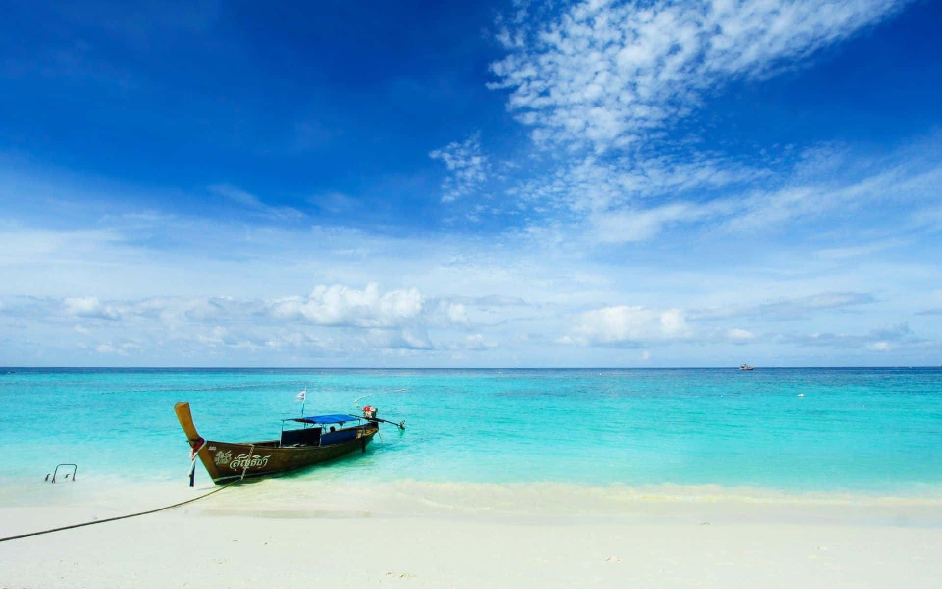 Thailand Beach 桌布 壁紙 — 一艘傳統木製長尾船停泊在純白沙灘上，旁邊是碧綠海水，上方是廣闊藍天，點綴著幾朵白雲。