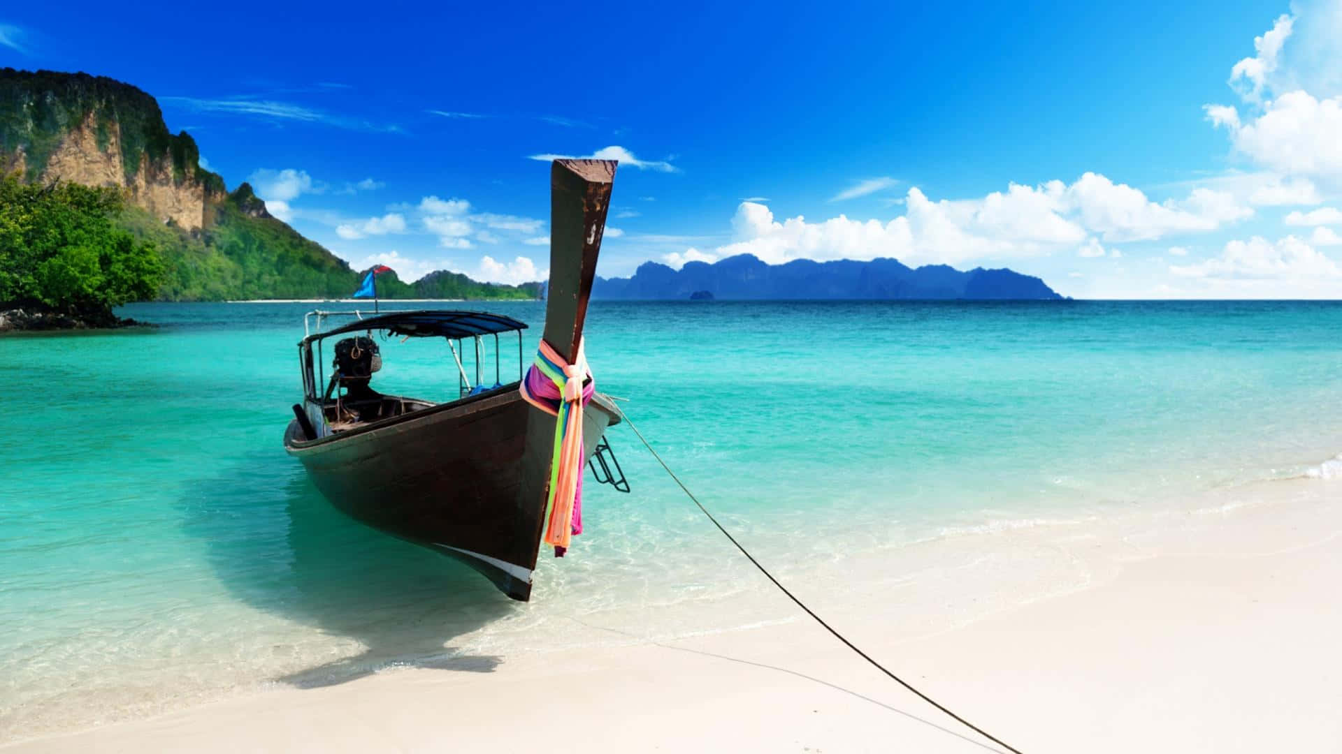 Bali Beach 桌布 壁紙 — 一艘傳統長尾船停泊在 pristine 白色沙灘上，四周是碧綠的海水和鬱鬱蔥蔥的綠色懸崖，頭頂是明亮的藍天。