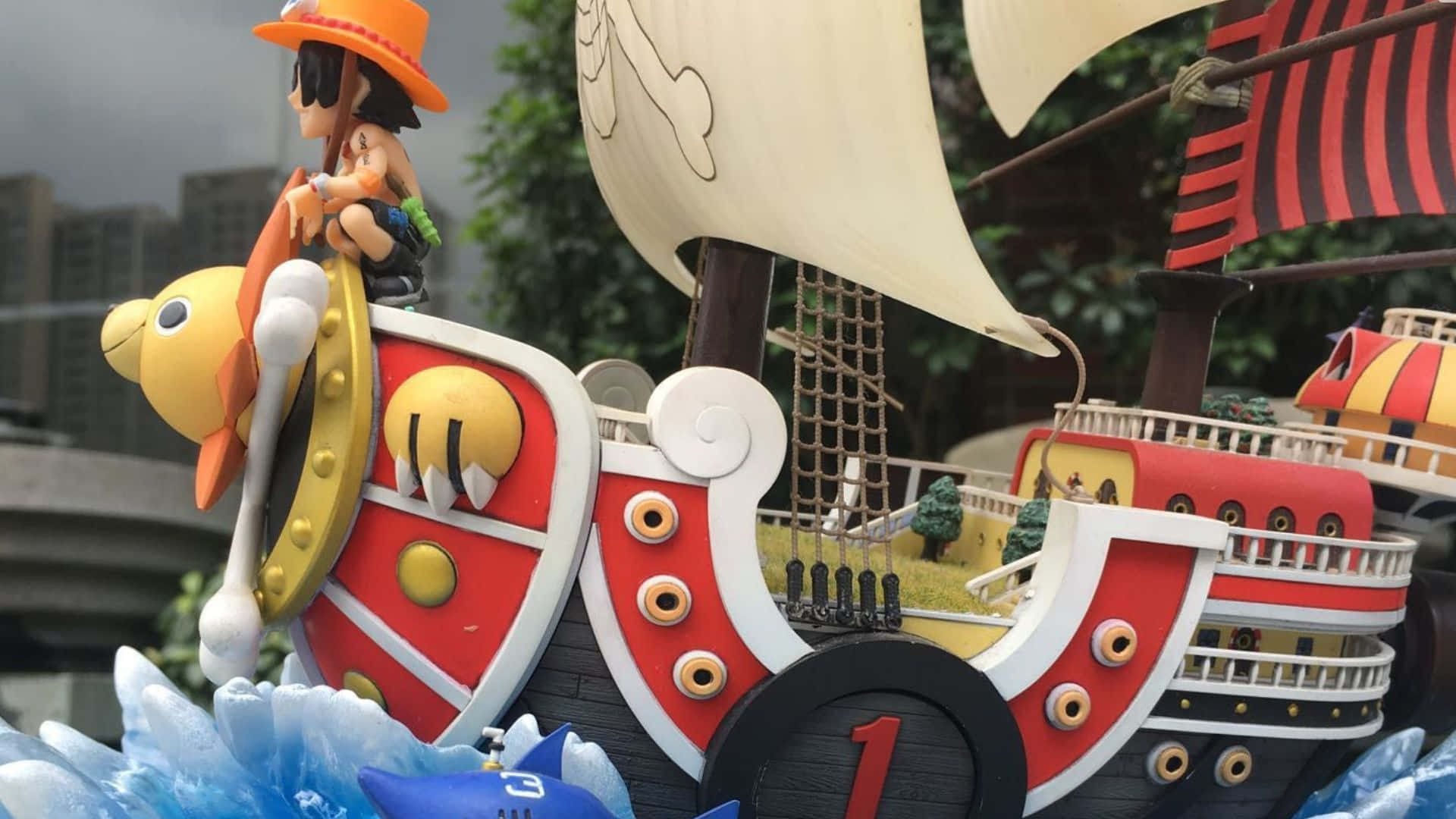Going Merry 桌布 壁紙 — 一艘充滿活力的動漫風格海盜船，船上有一位戴草帽的船長人物，矗立在風格化的藍色波浪中，背景是模糊的城市天際線。