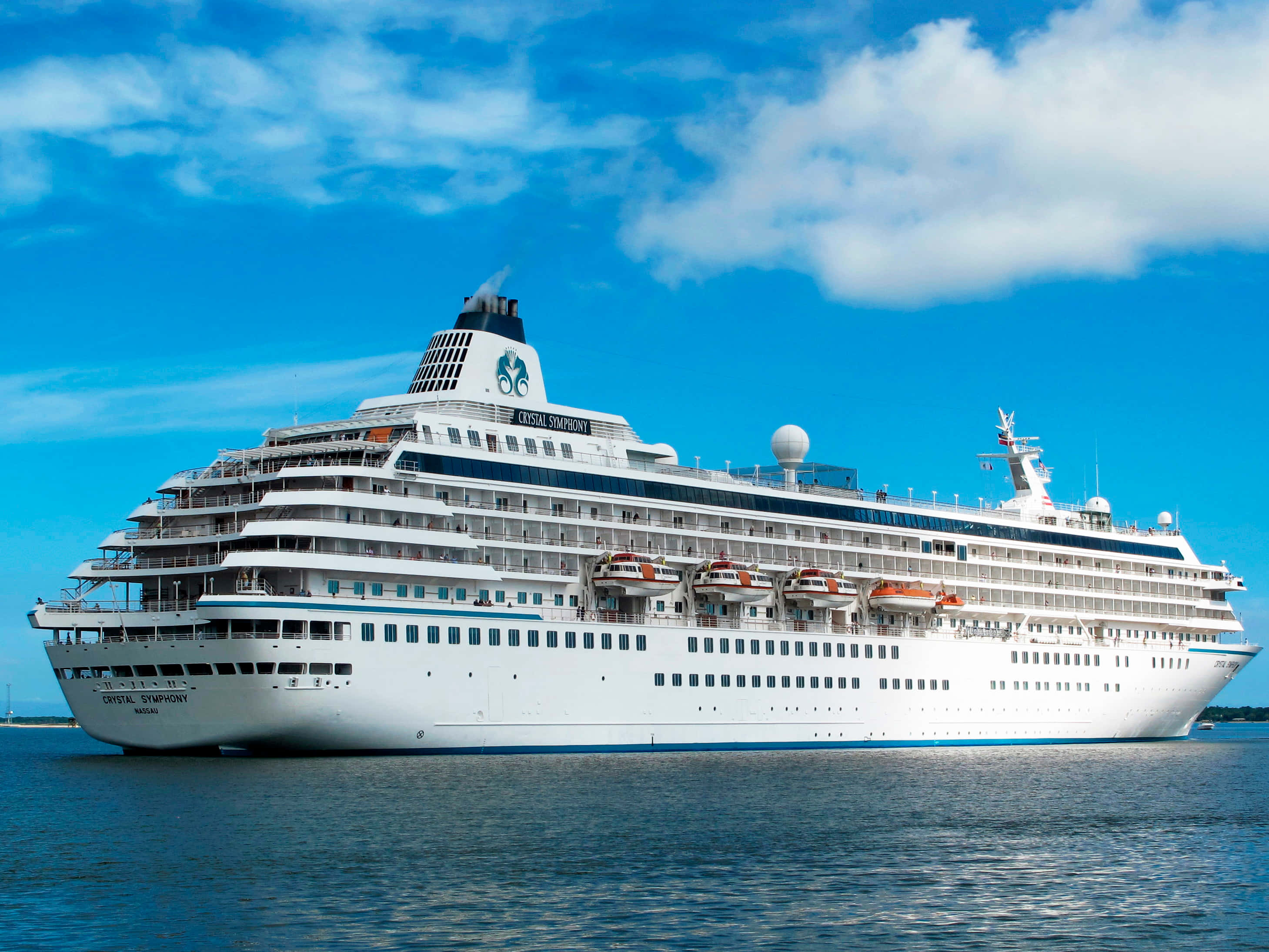 Cruise Ship 桌布 壁紙 — 一艘名為 Crystal Symphony 的巨型白色郵輪在深藍色海面上平靜航行，天空湛藍，白雲朵朵。