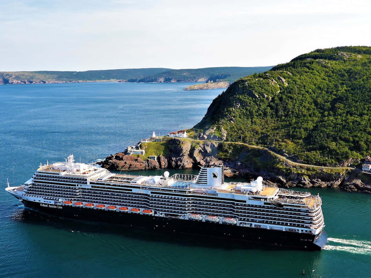 Cruise Ship 桌布 壁紙 — 一艘大型郵輪在碧綠色的海水中航行，旁邊是鬱鬱蔥蔥的綠色懸崖，懸崖上有一條蜿蜒的道路和一座燈塔。
