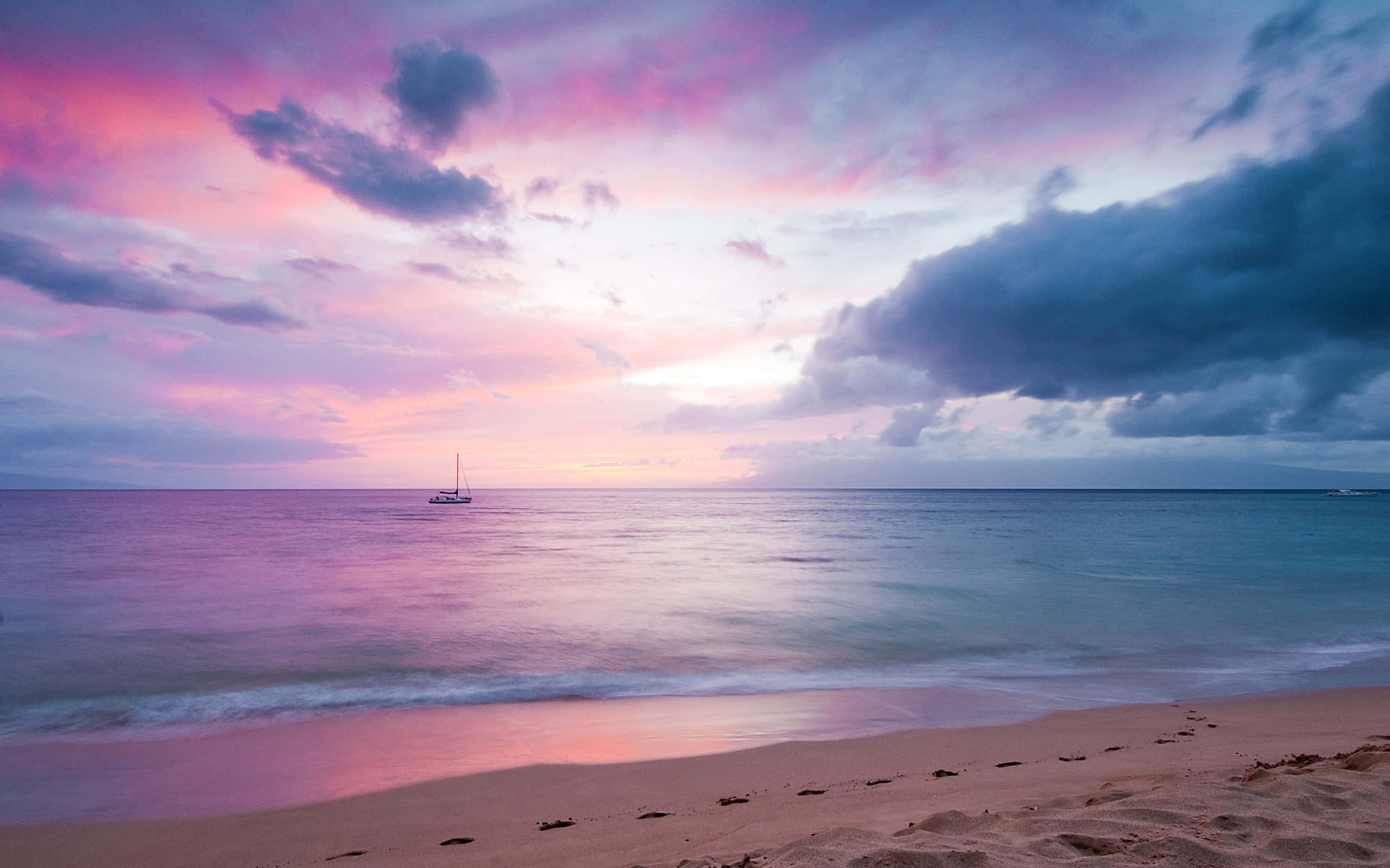 Aesthetic Beach 桌布 壁紙 — 一艘孤獨的帆船在沙灘上戲劇性的粉紅色和紫色日落天空下，停泊在平靜的水面上。