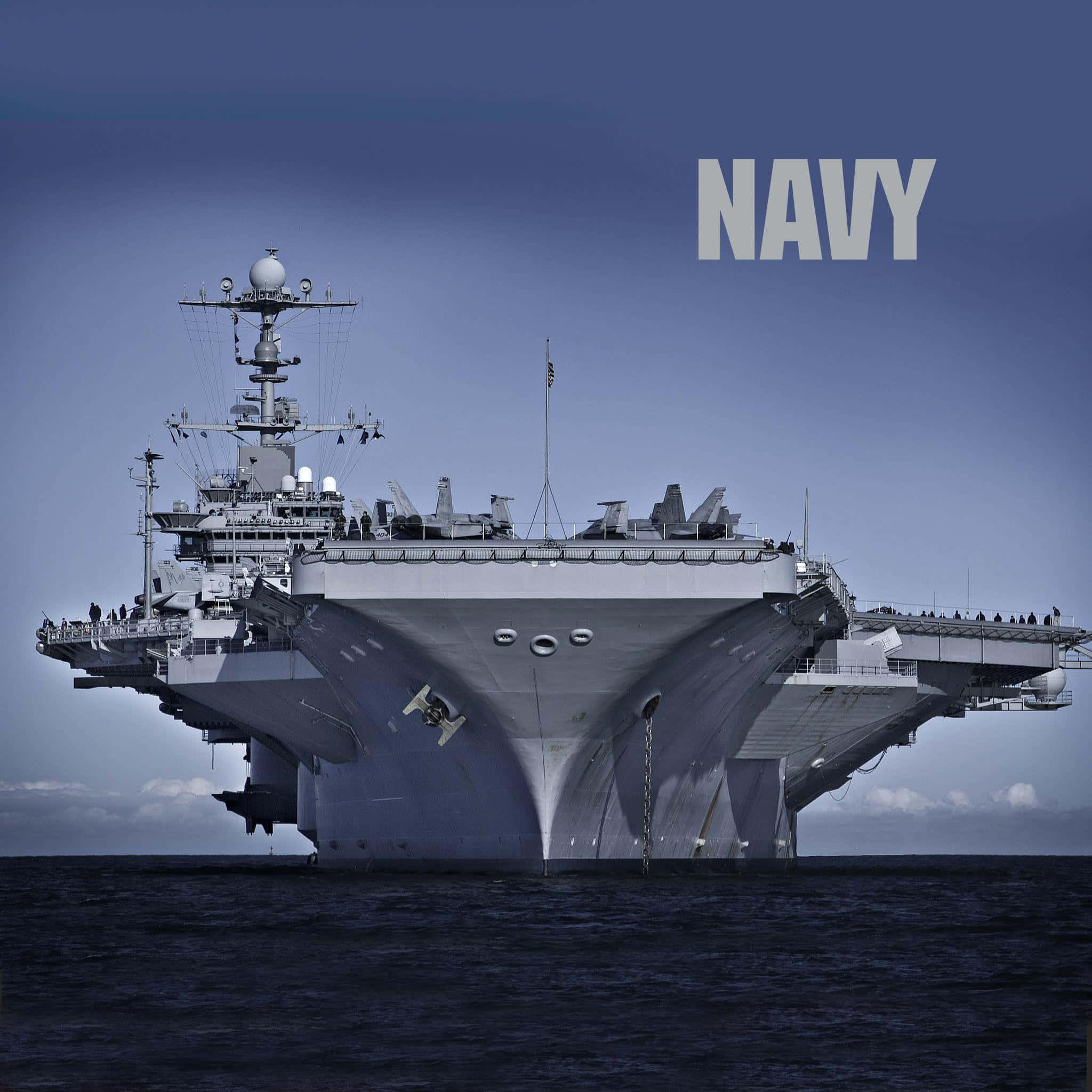 Navy 桌布 壁紙 — 一艘巨大的灰色海軍航空母艦在深藍色的天空下主宰海洋，並以粗體白色字母寫著NAVY。
