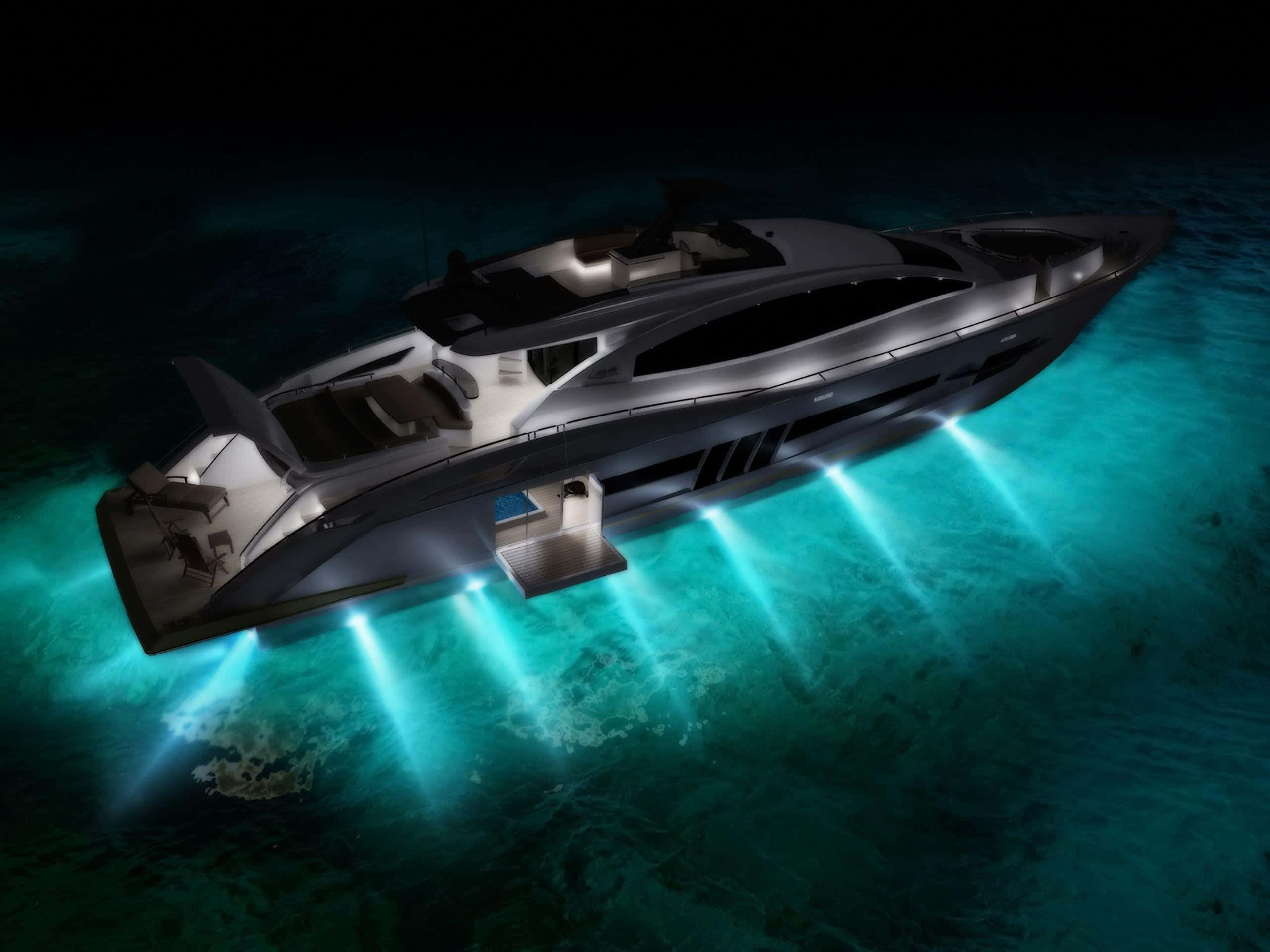 Yacht 桌布 壁紙 — 一艘時尚的豪華遊艇在夜間滑過發光的碧綠海水，水下燈光照亮下方的海床。