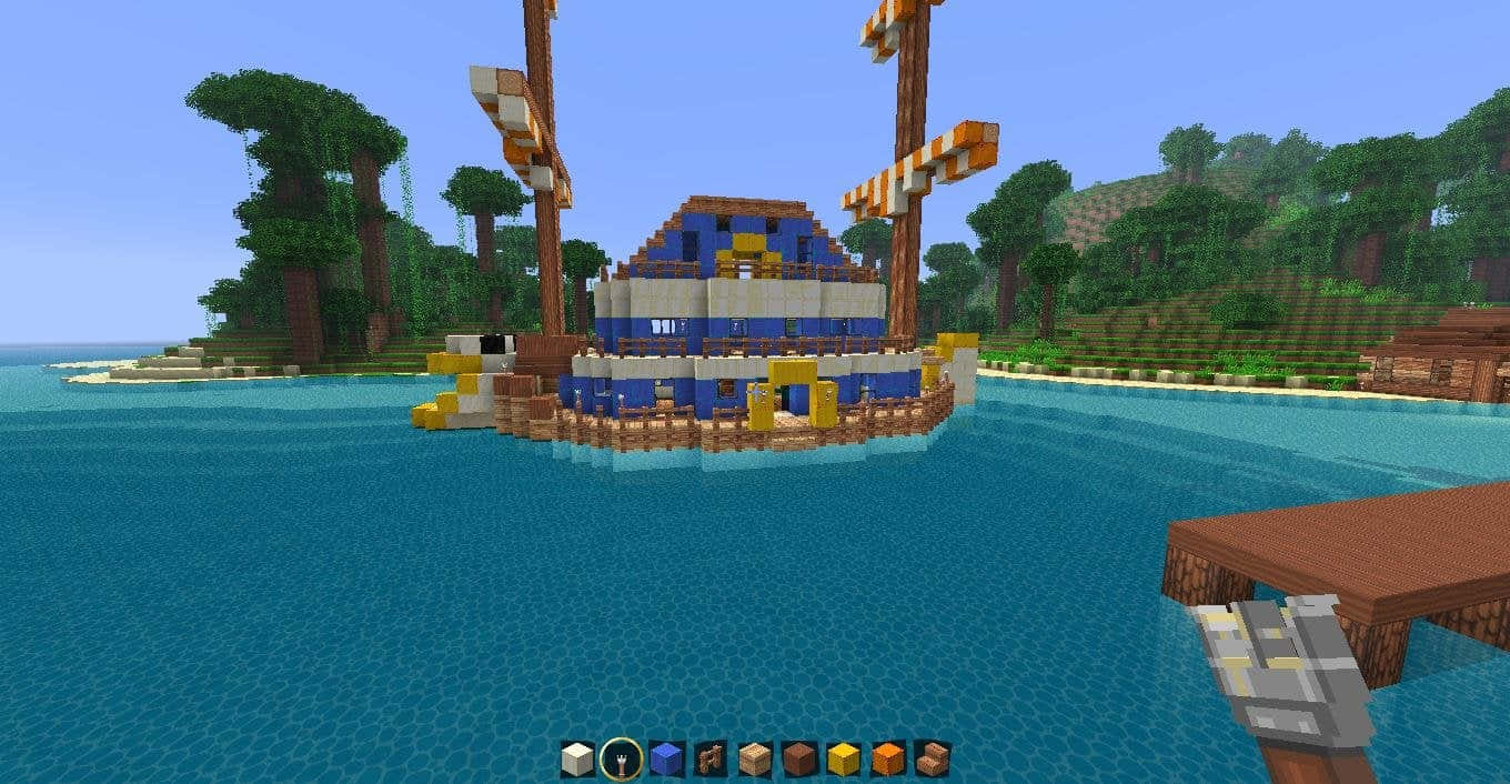 Baratie 桌布 壁紙 — 一艘由藍色和白色方塊組成的像素化Minecraft海盜船漂浮在森林海岸附近的碧綠水面上。