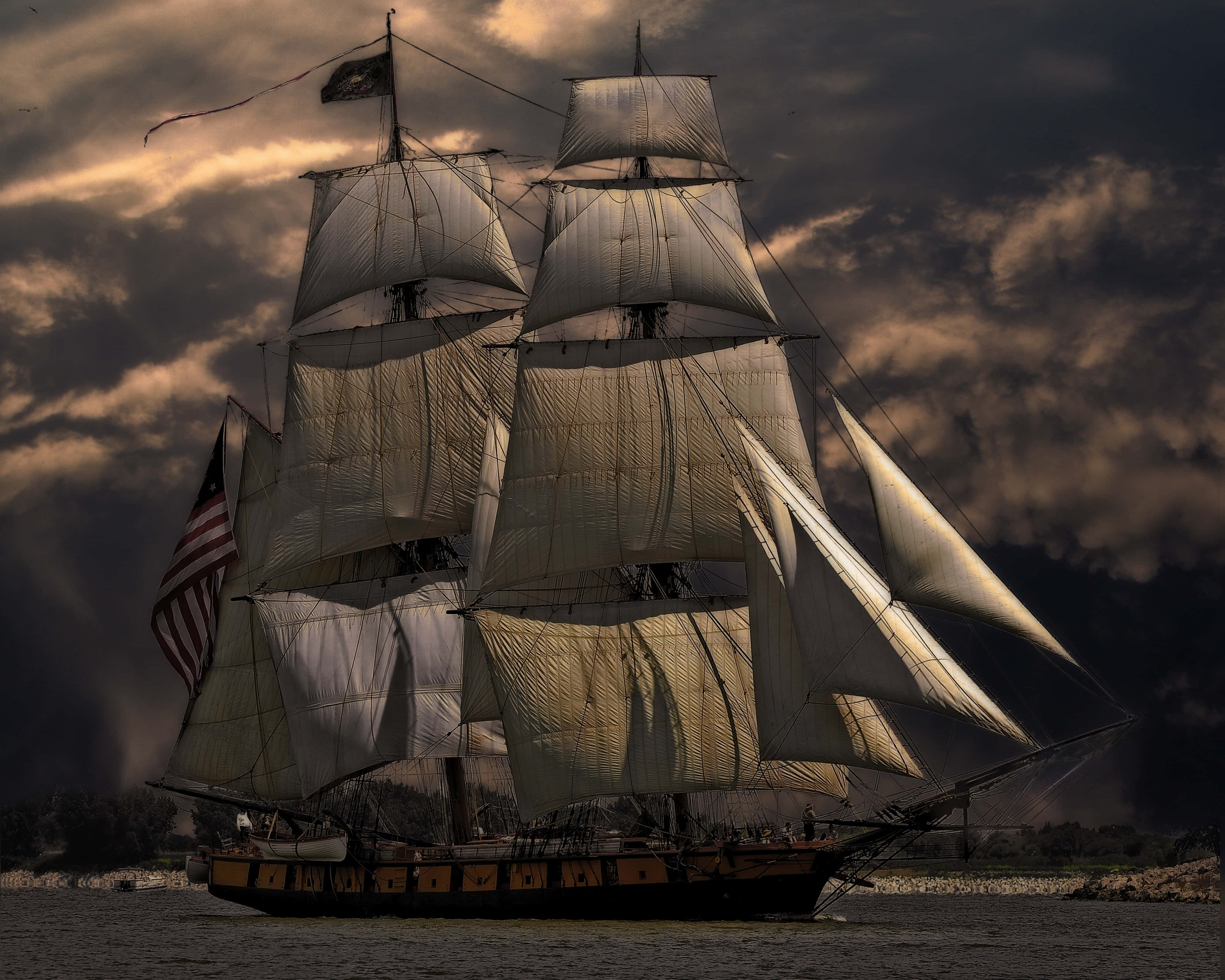 Ship 桌布 壁紙 — 一艘雄偉的大帆船，鼓滿風帆，在平靜的水面上滑行，背景是戲劇性的暴風雨天空，被金色的夕陽餘暉照亮。