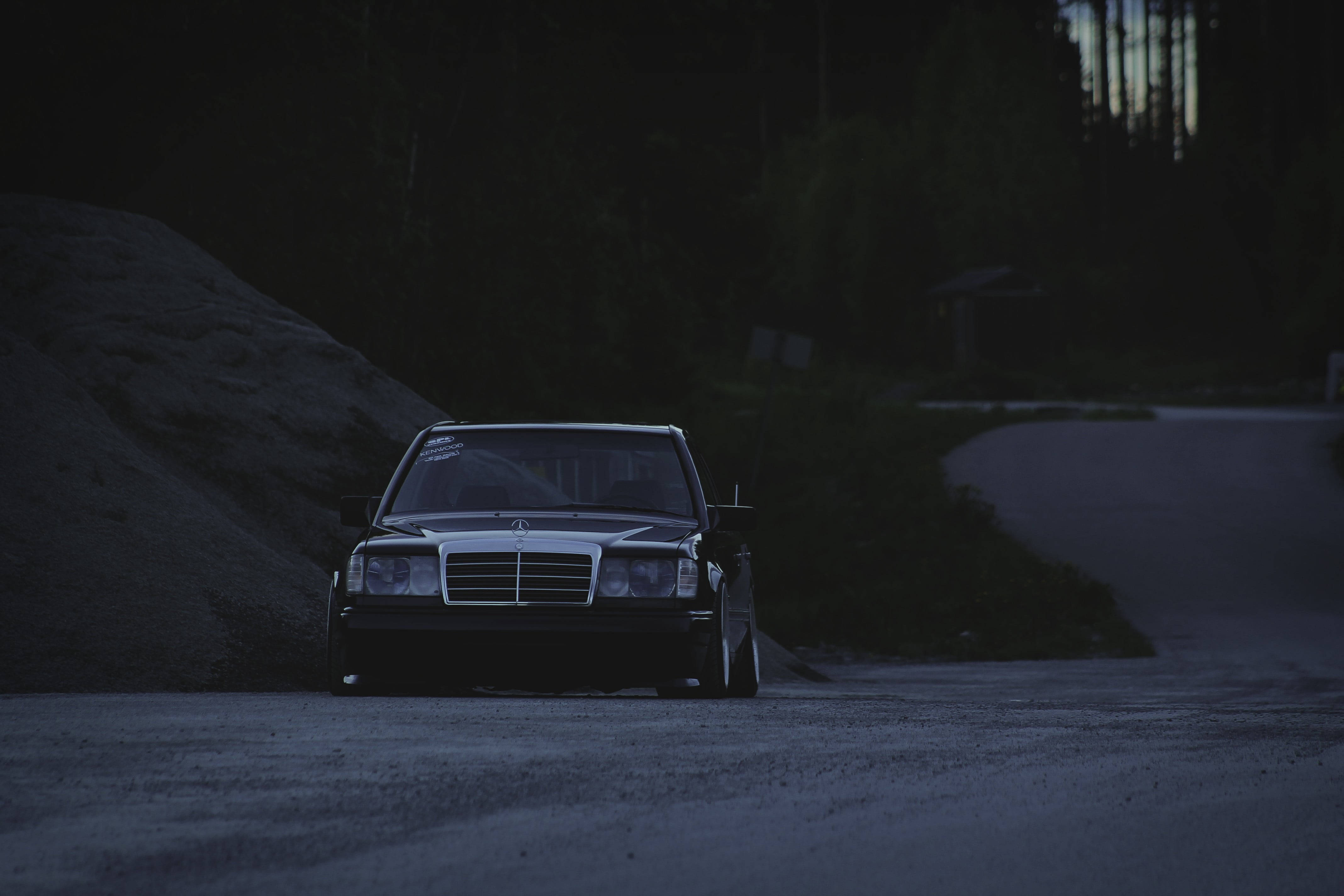 HD 桌布 壁紙 — 一輛 vintage Mercedes-Benz 房車在黃昏時停泊在碎石路上，背景是黑暗的森林。