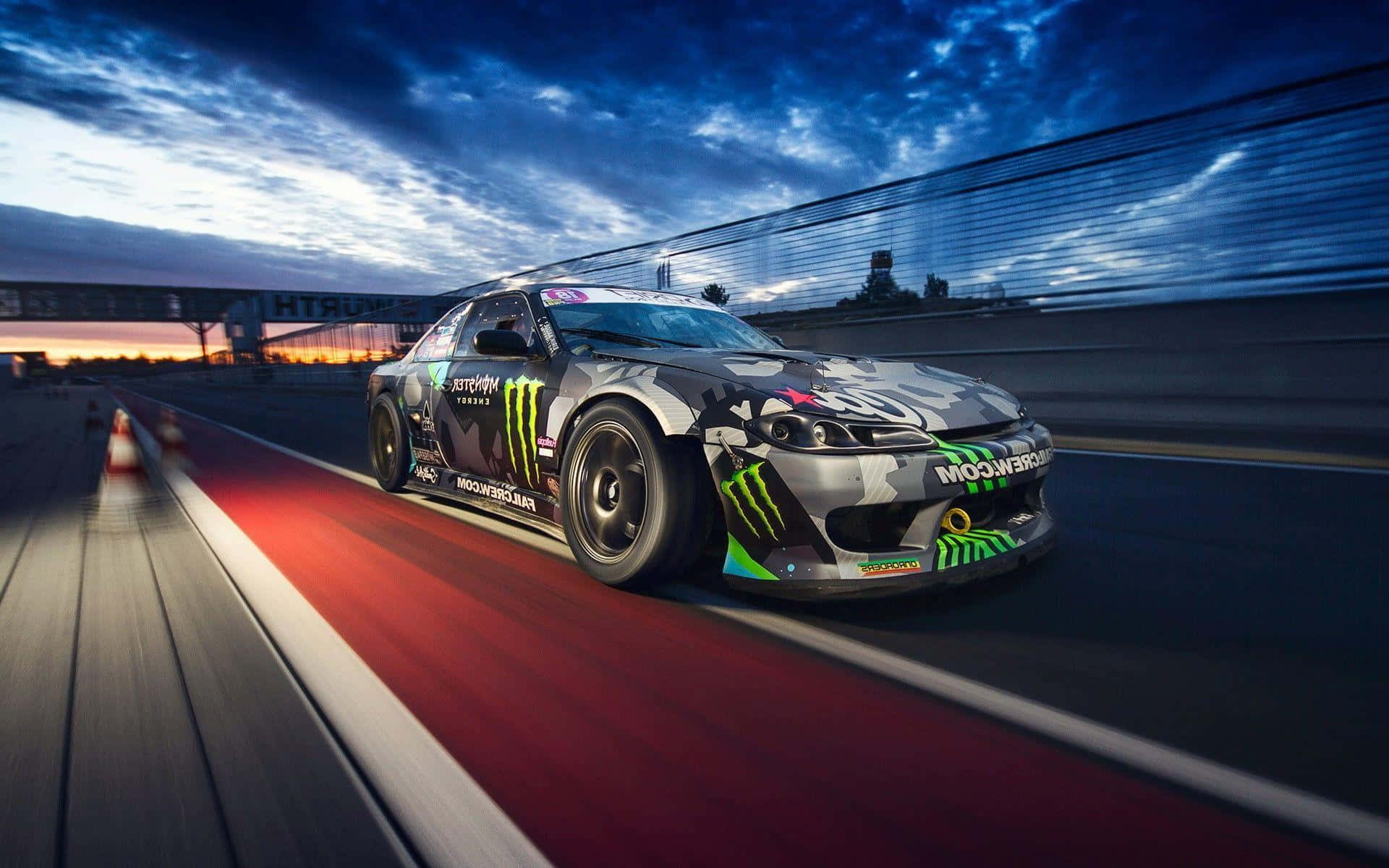 Monster Energy 桌布 壁紙 — 一輛Monster Energy飄移車在黃昏時分沿著賽道疾馳，帶有動態模糊和戲劇性的天空。