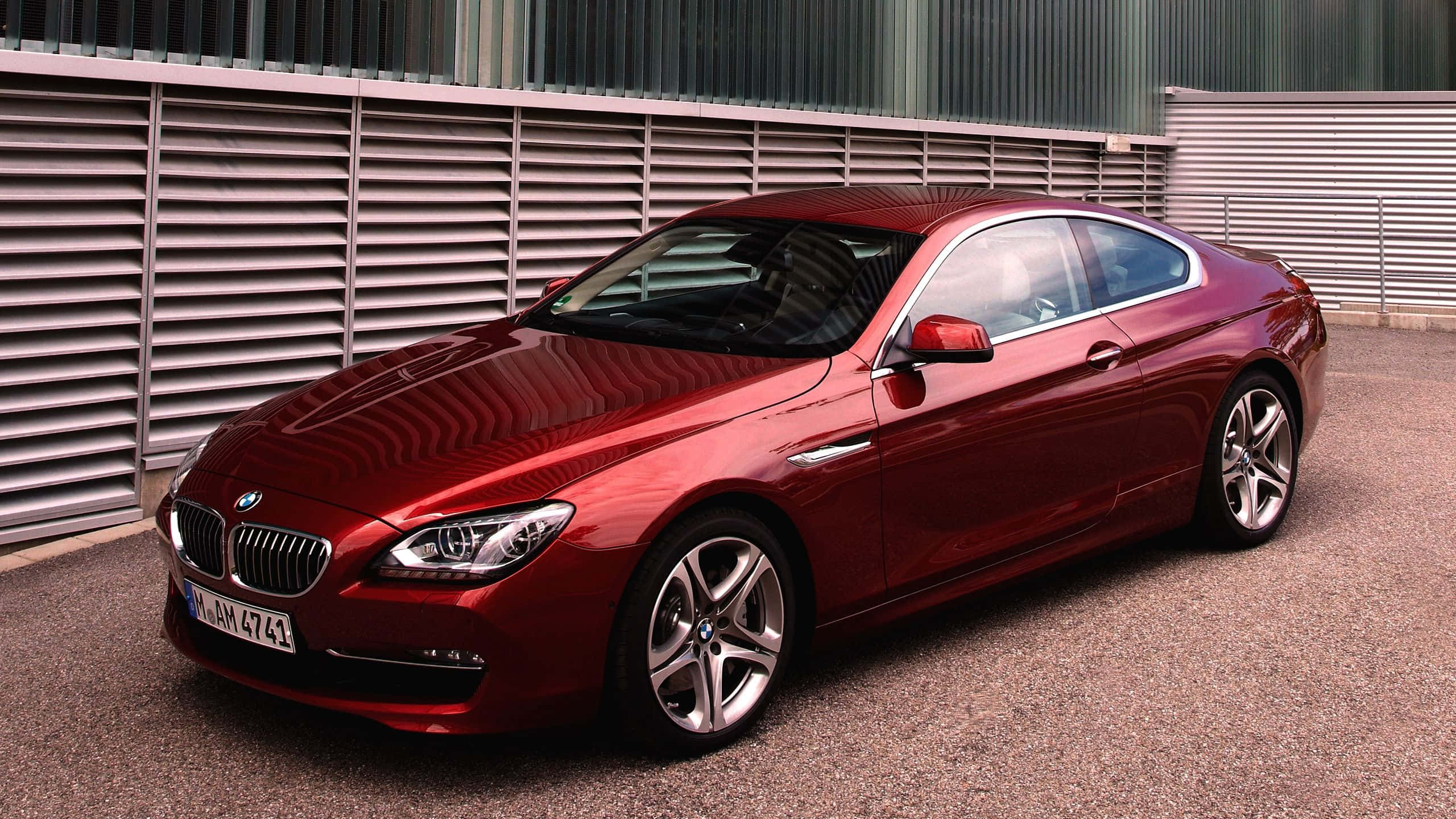 Bmw 6 Series 桌布 壁紙 — 一輛亮紅色BMW 6系雙門轎跑車停在碎石上，旁邊是金屬條紋牆，在明亮的日光下。