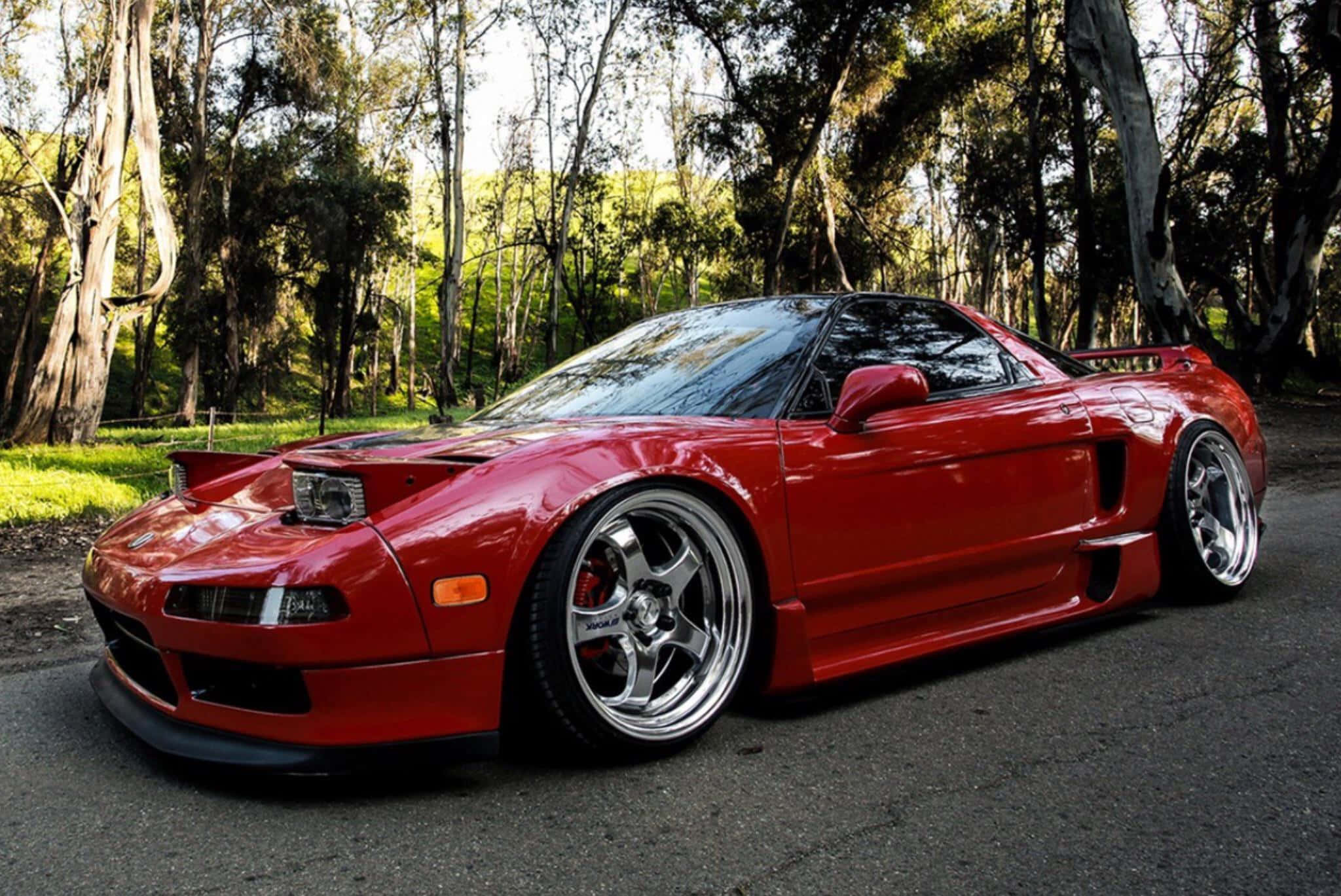 Honda Nsx 桌布 壁紙 — 一輛亮紅色改裝跑車停在森林道路上，陽光透過高大的樹木灑落。