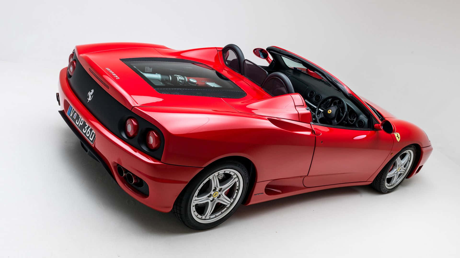 Ferrari 360 Modena 桌布 壁紙 — 一輛亮紅色法拉利360 Spider開篷跑車，車頂敞開，在純白工作室背景襯托下展示其流暢曲線和黑色內飾。
