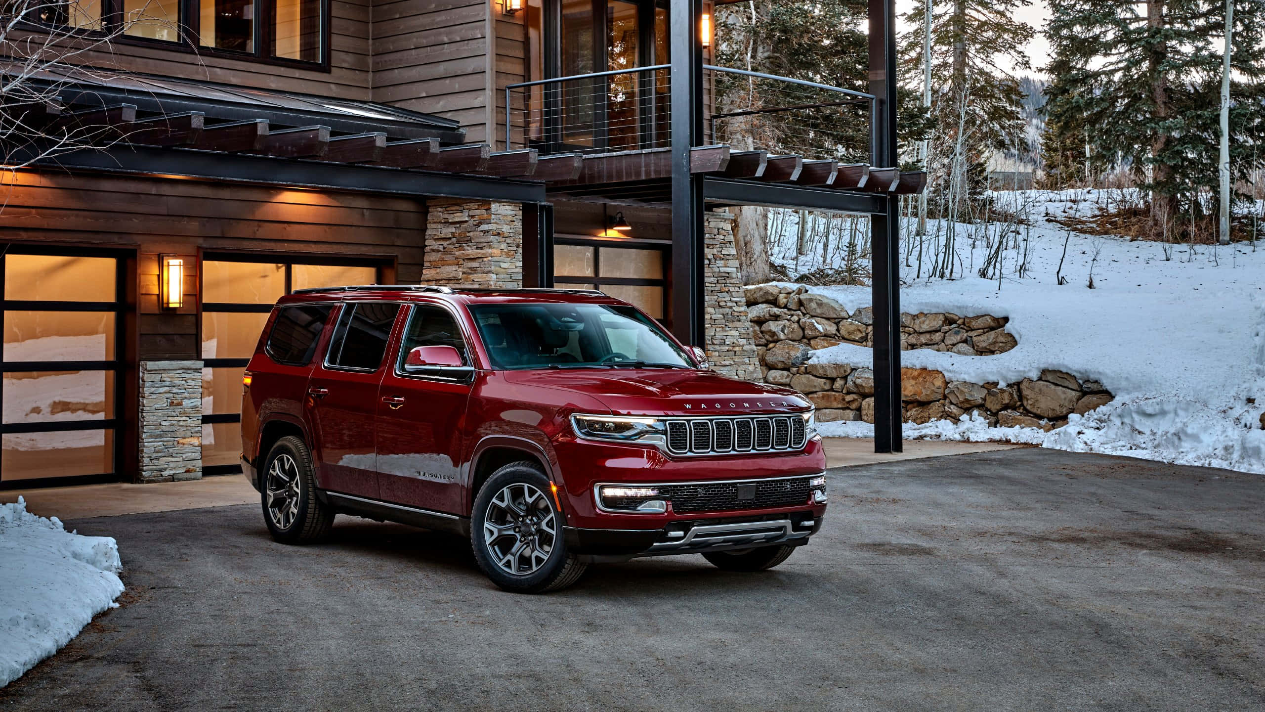 Jeep Wagoneer 桌布 壁紙 — 一輛亮紅色的Jeep Grand Cherokee停在一棟現代木屋前，地面和背景樹木都被雪覆蓋。