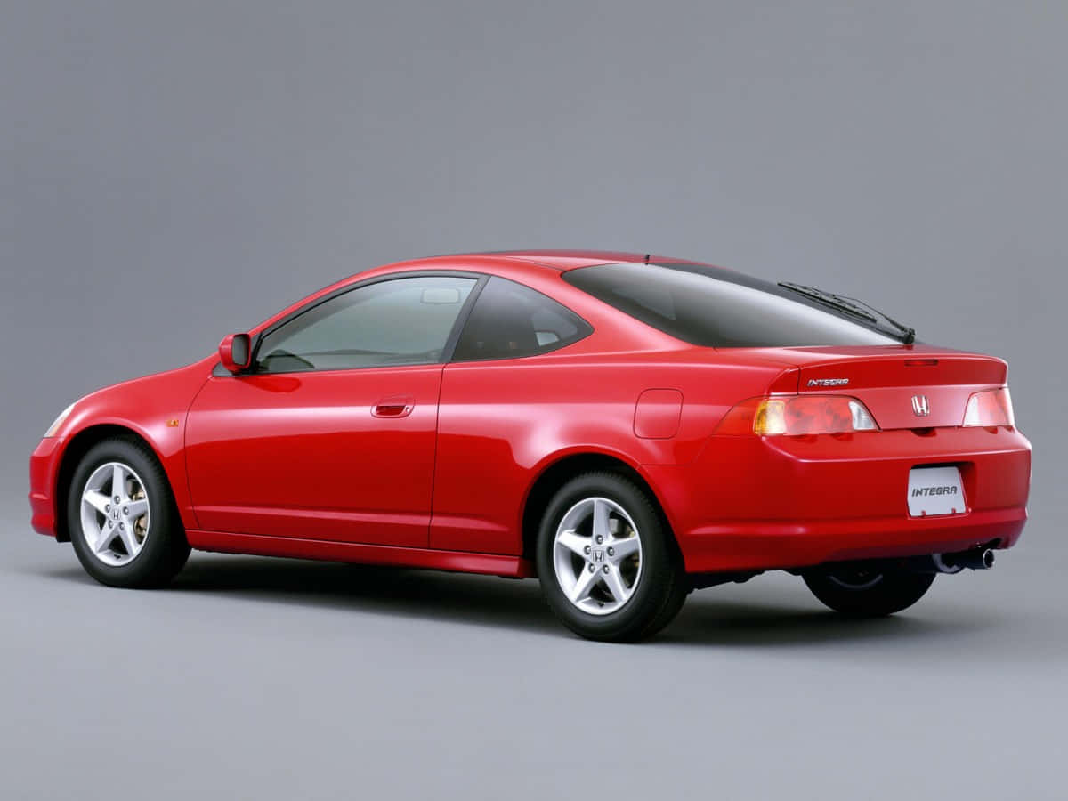 Honda Integra 桌布 壁紙 — 一輛亮紅色的本田Integra轎跑車以四分之三後視圖展示在純灰色攝影棚背景前。