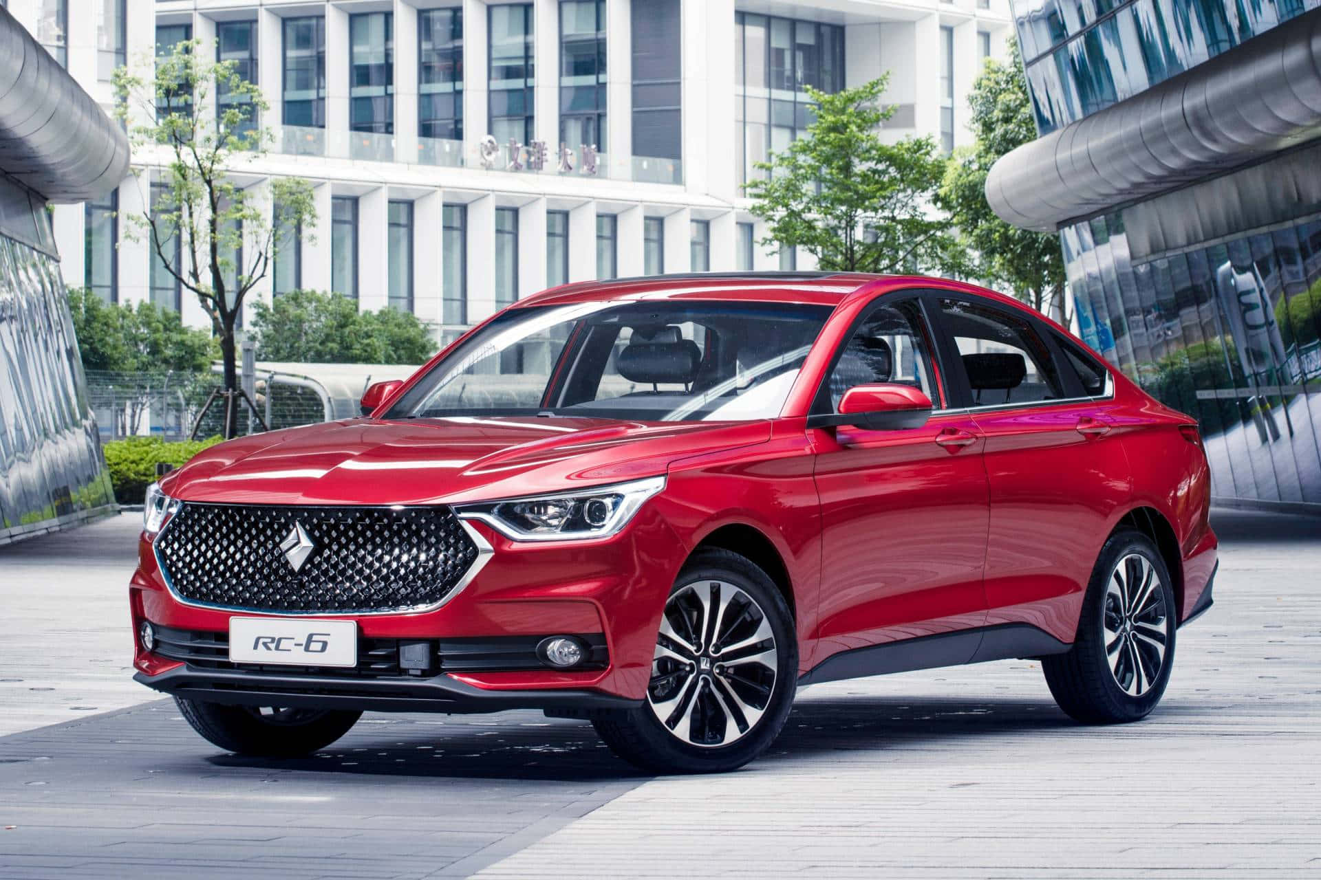 Baojun 桌布 壁紙 — 一輛亮紅色轎車停泊在現代都市廣場上，背景有玻璃建築和綠樹。