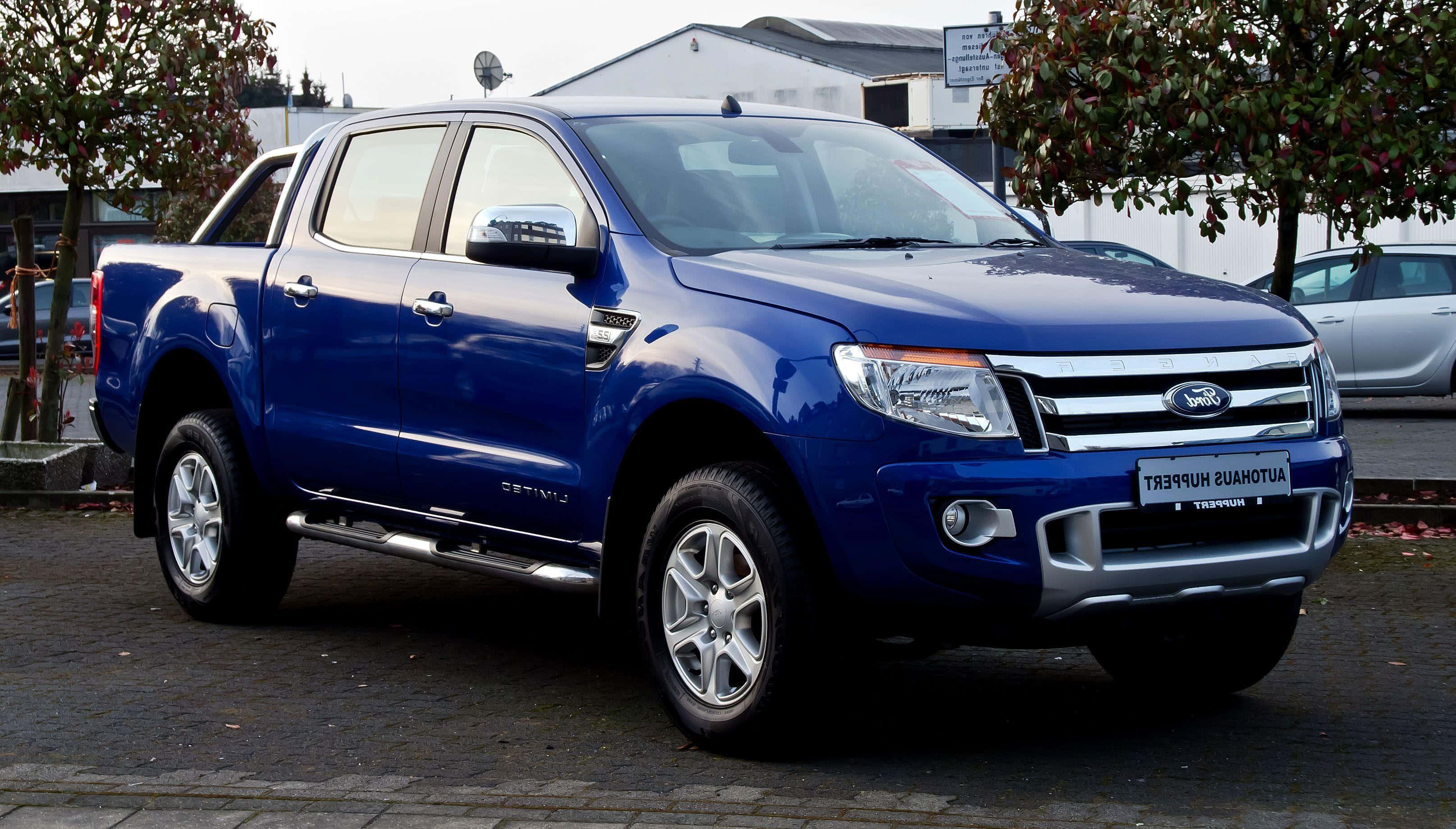 Ford Ranger 桌布 壁紙 — 一輛亮藍色福特Ranger pickup貨車停泊在鋪砌的停車場，背景有樹木和建築物。