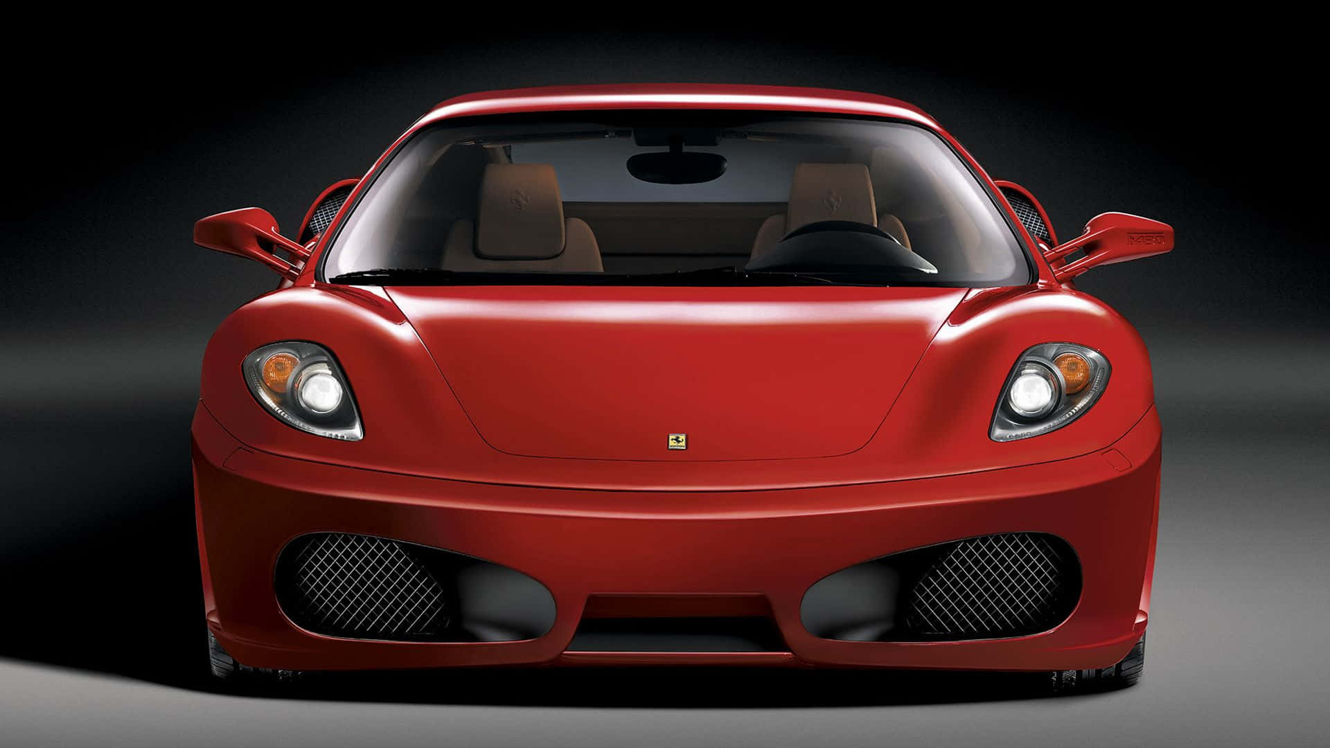 Ferrari F430 桌布 壁紙 — 一輛亮面紅色法拉利跑車，車頭燈亮起，在深色漸變背景前以戲劇性的攝影棚拍攝捕捉。