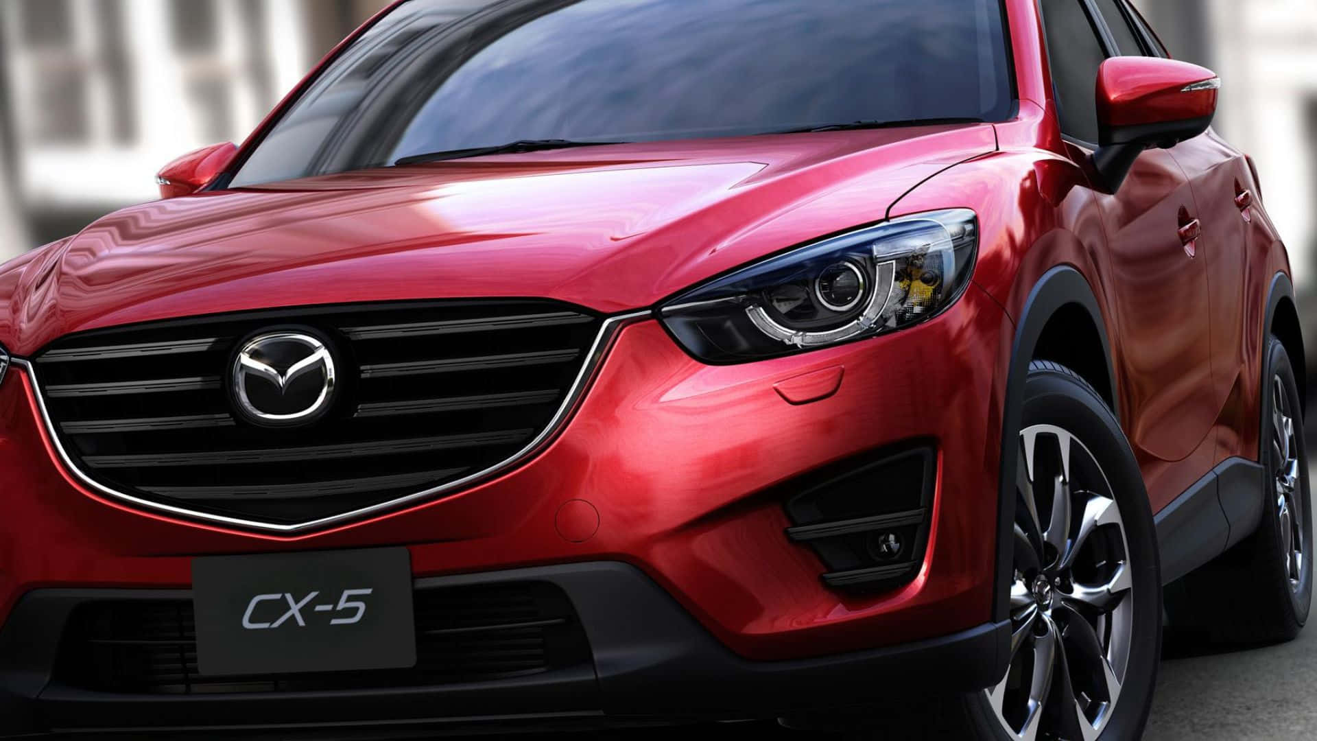 Mazda Cx-5 桌布 壁紙 — 一輛亮麗的紅色Mazda CX-5 SUV在明亮的日光下展示其時尚現代設計，配備銳利頭燈和鍍鉻飾件。