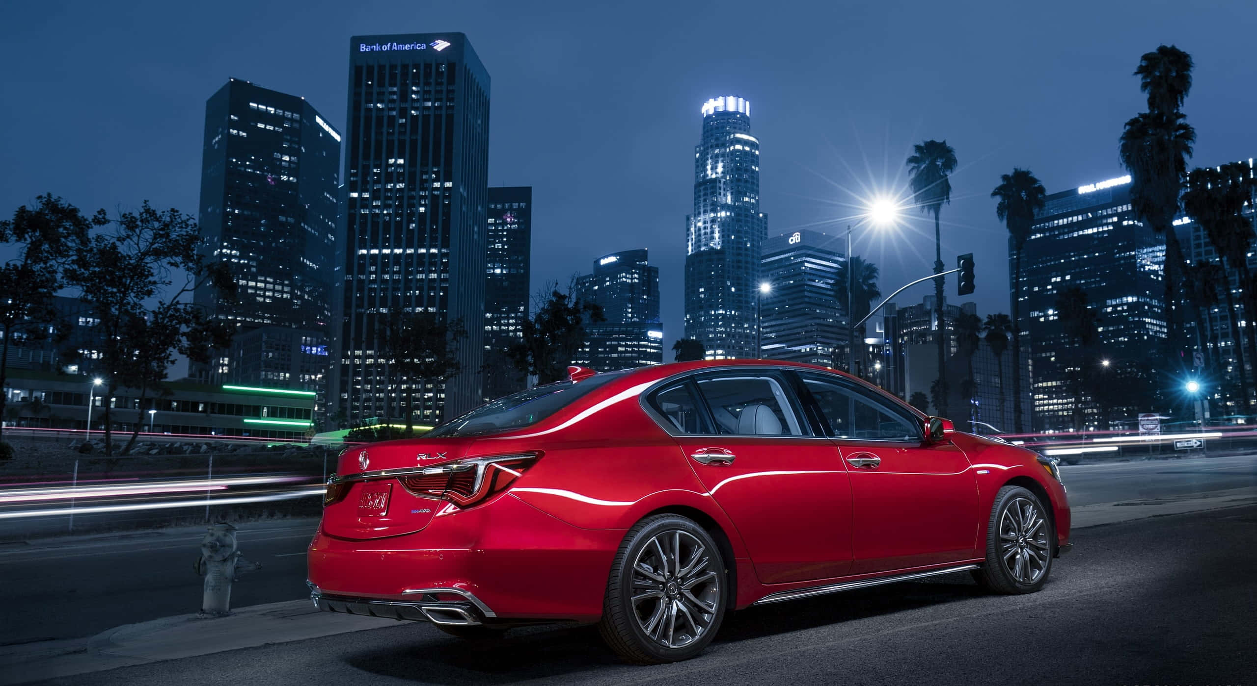 Acura Rlx 桌布 壁紙 — 一輛亮麗的紅色房車在夜晚穿過霓虹燈閃爍的城市景觀，伴隨著流動的車流和背後閃耀的摩天大樓。