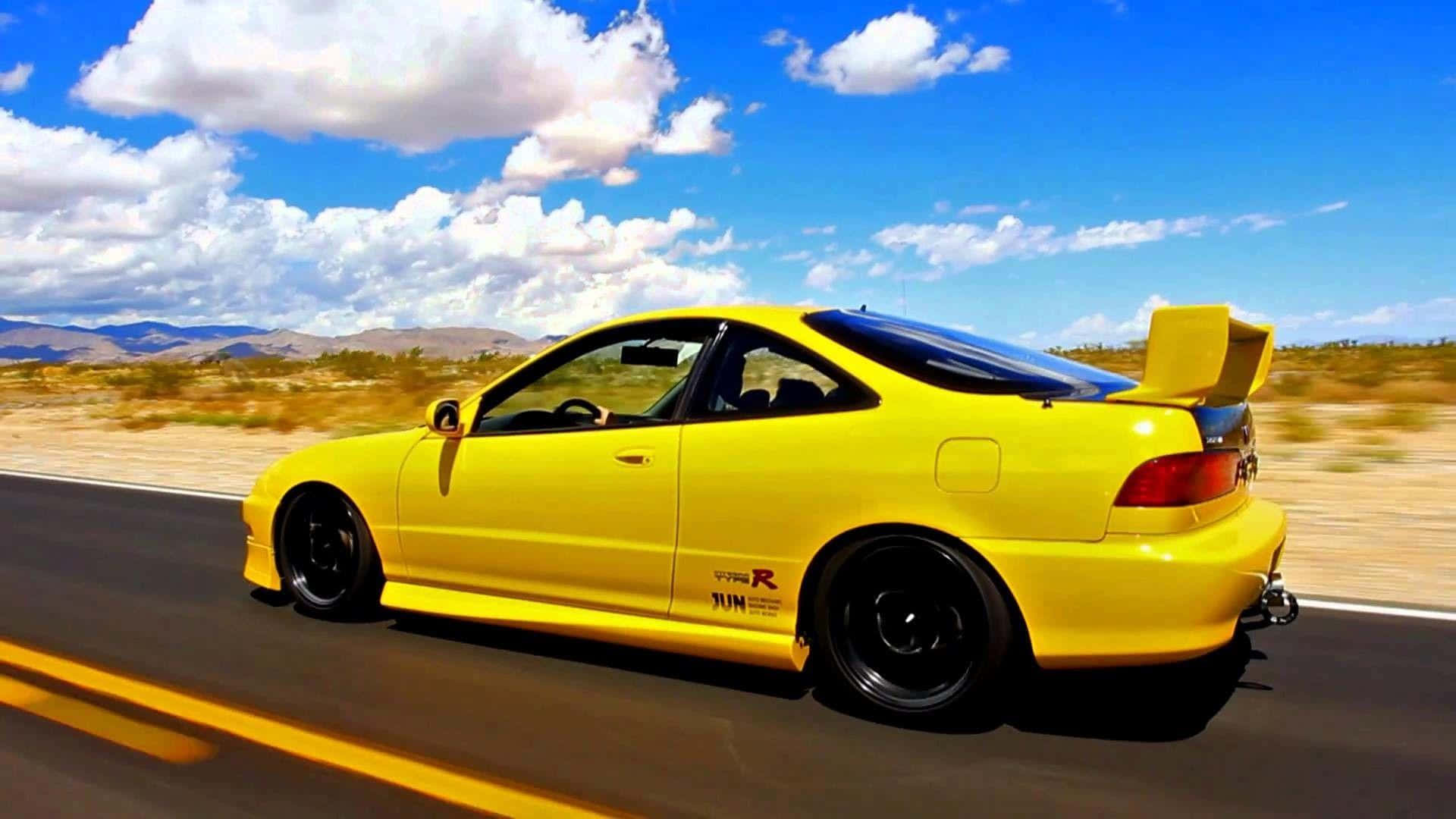 Acura Integra 桌布 壁紙 — 一輛亮黃色改裝跑車在沙漠高速公路上飛馳，天空湛藍，白雲朵朵。