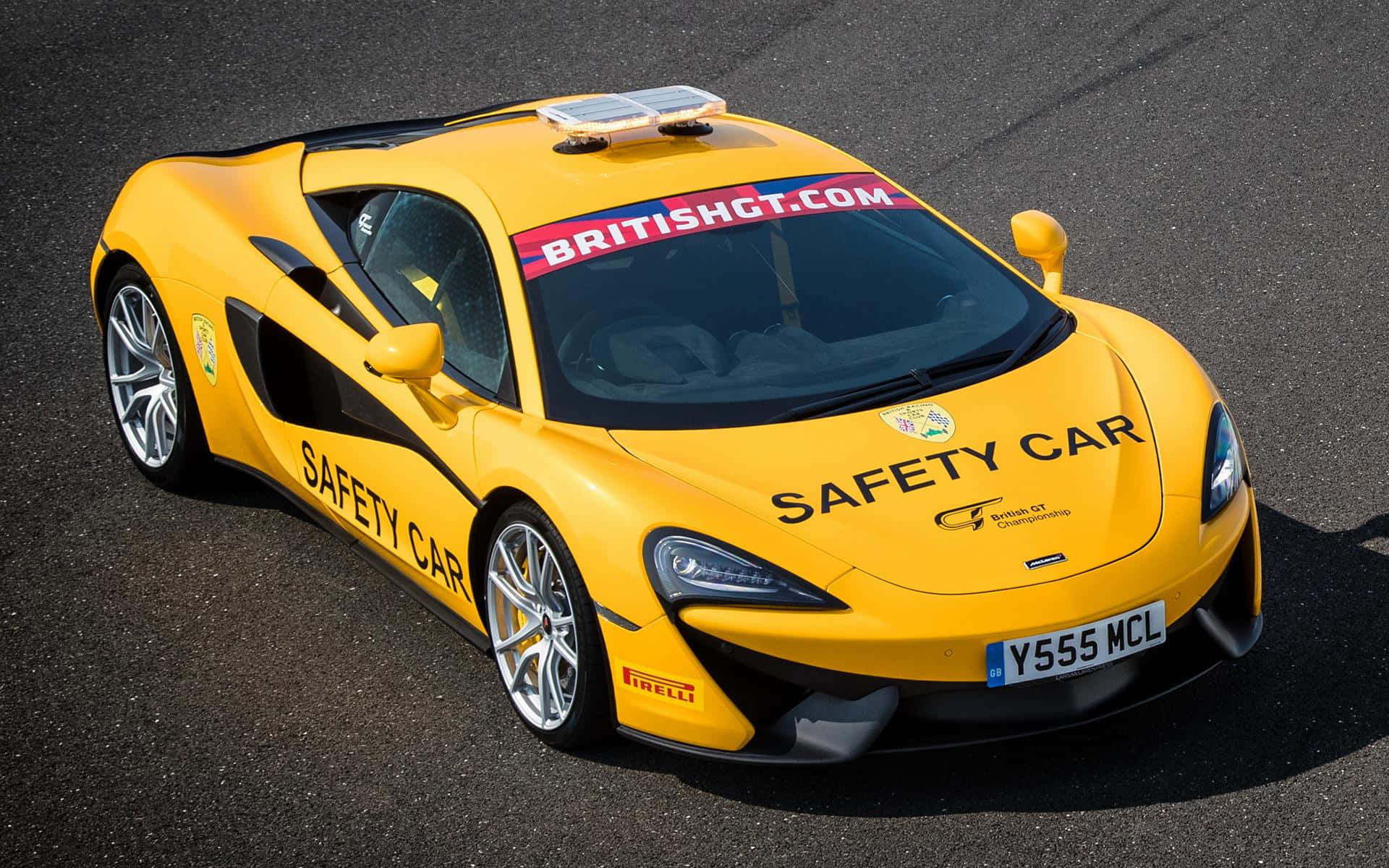 賽道上流銀色安全戒備車輛 壁紙 — 一輛亮黃色的McLaren 570S安全車，帶有'SAFETY CAR'貼紙和British GT品牌標誌，停在瀝青路面上。