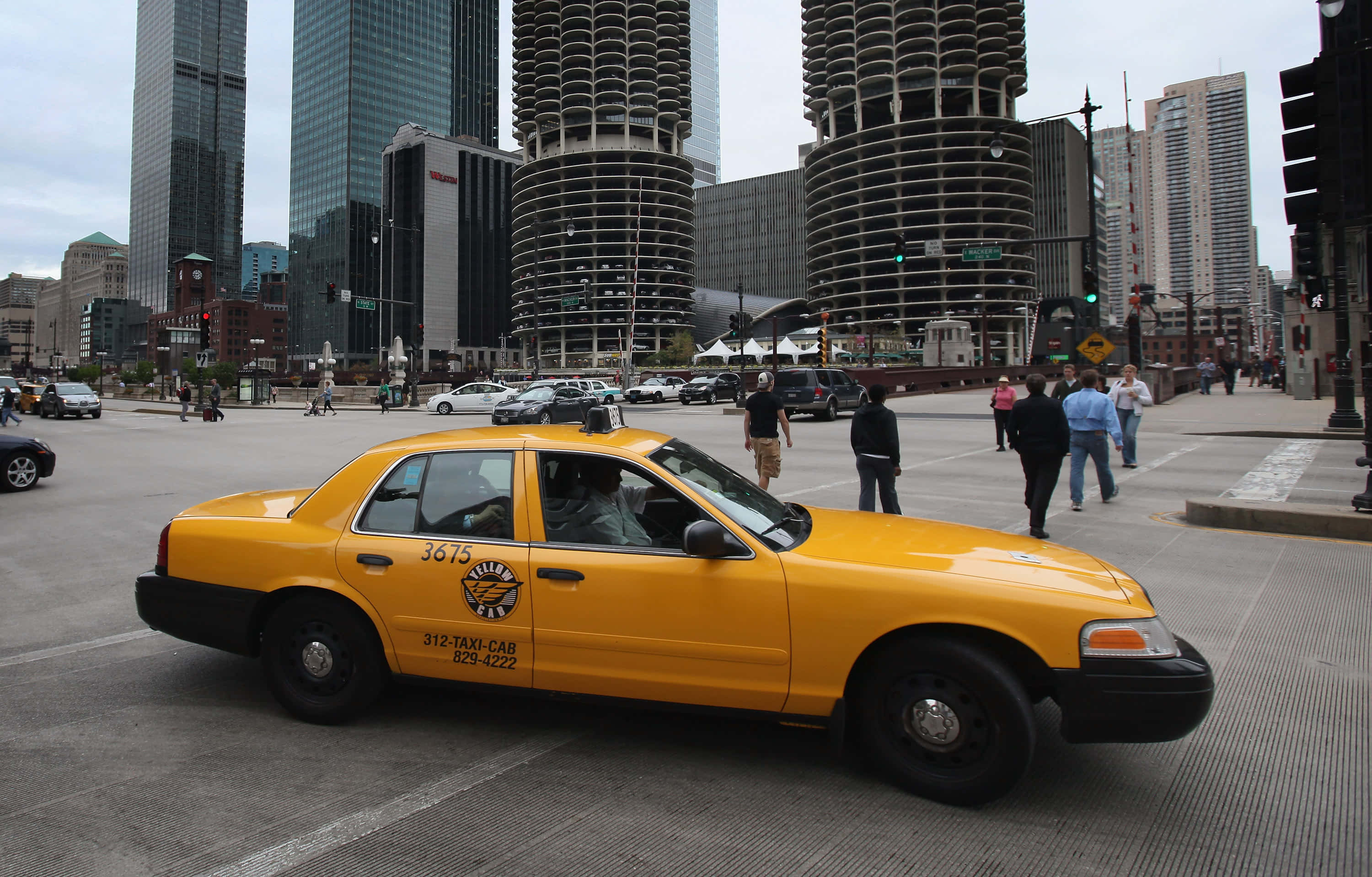 taxi 桌布 壁紙 — 一輛亮黃色的出租車在繁華的城市街道上行駛，街道兩旁是高聳的摩天大樓和行人。