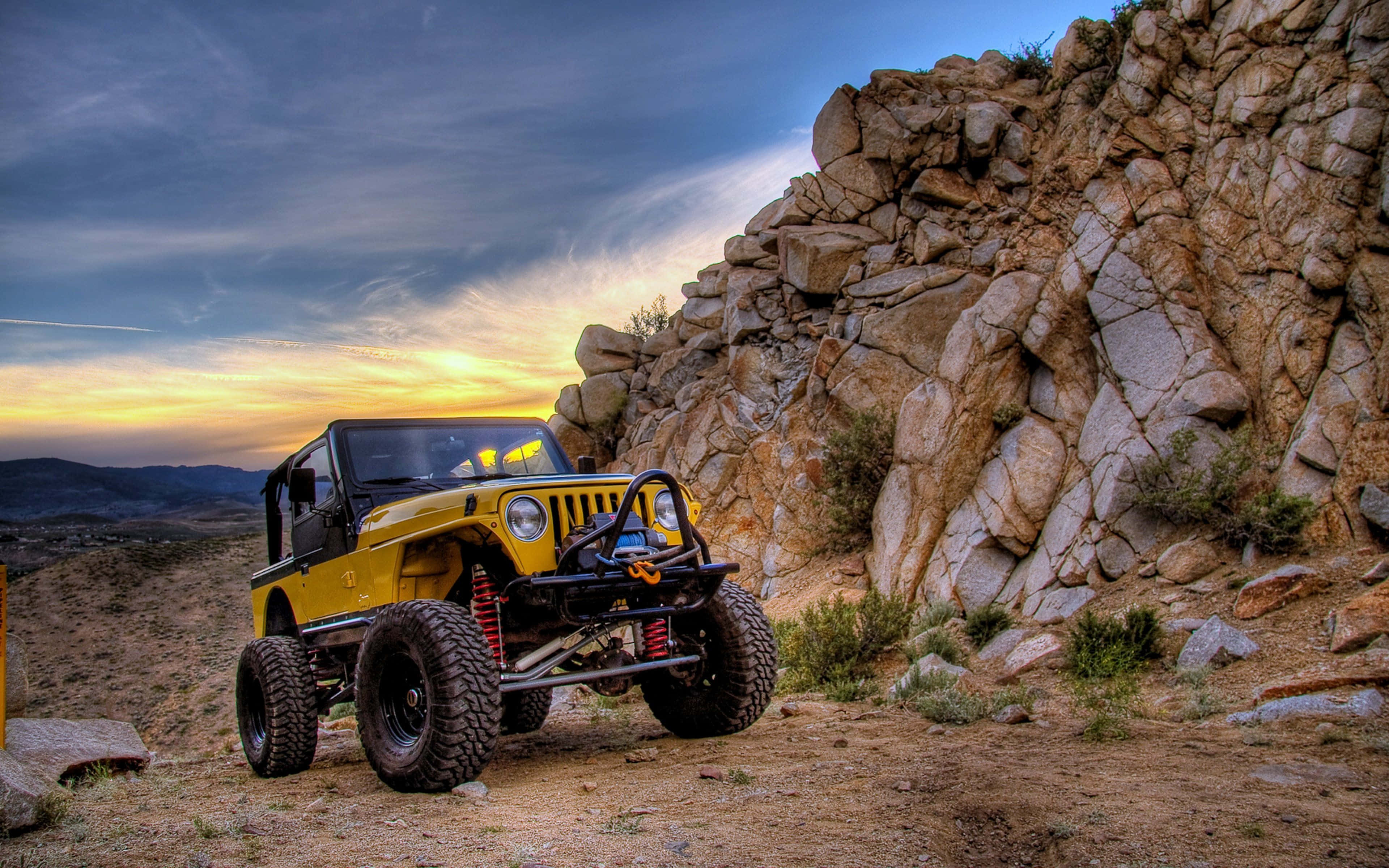 Jeep Cj 桌布 壁紙 — 一輛亮黃色越野Jeep，配備紅色避震器，停在日落時分的岩石沙漠小徑上。