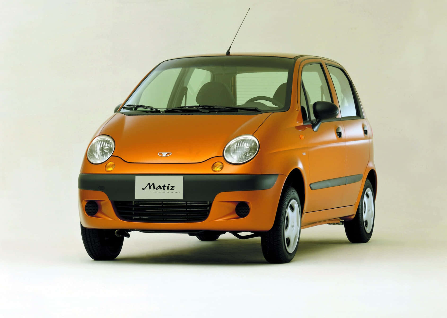 Daewoo 桌布 壁紙 — 一輛充滿活力的橙色Daewoo Matiz小型房車，在乾淨的攝影棚環境中，以純白色背景拍攝。