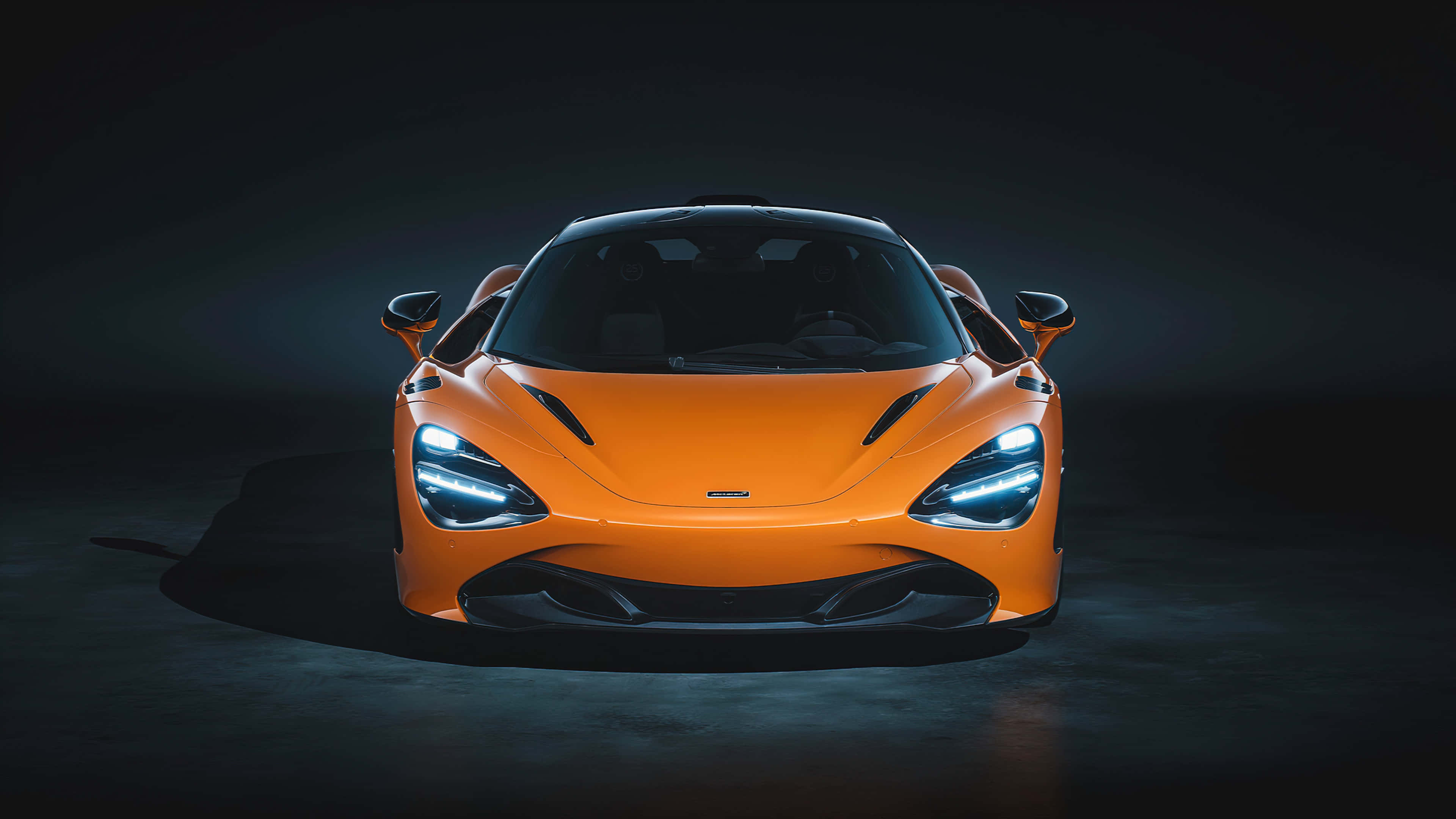 麥拿侖 桌布 壁紙 — 一輛充滿活力的橙色McLaren跑車在黑暗背景下，在戲劇性的工作室燈光下閃耀。