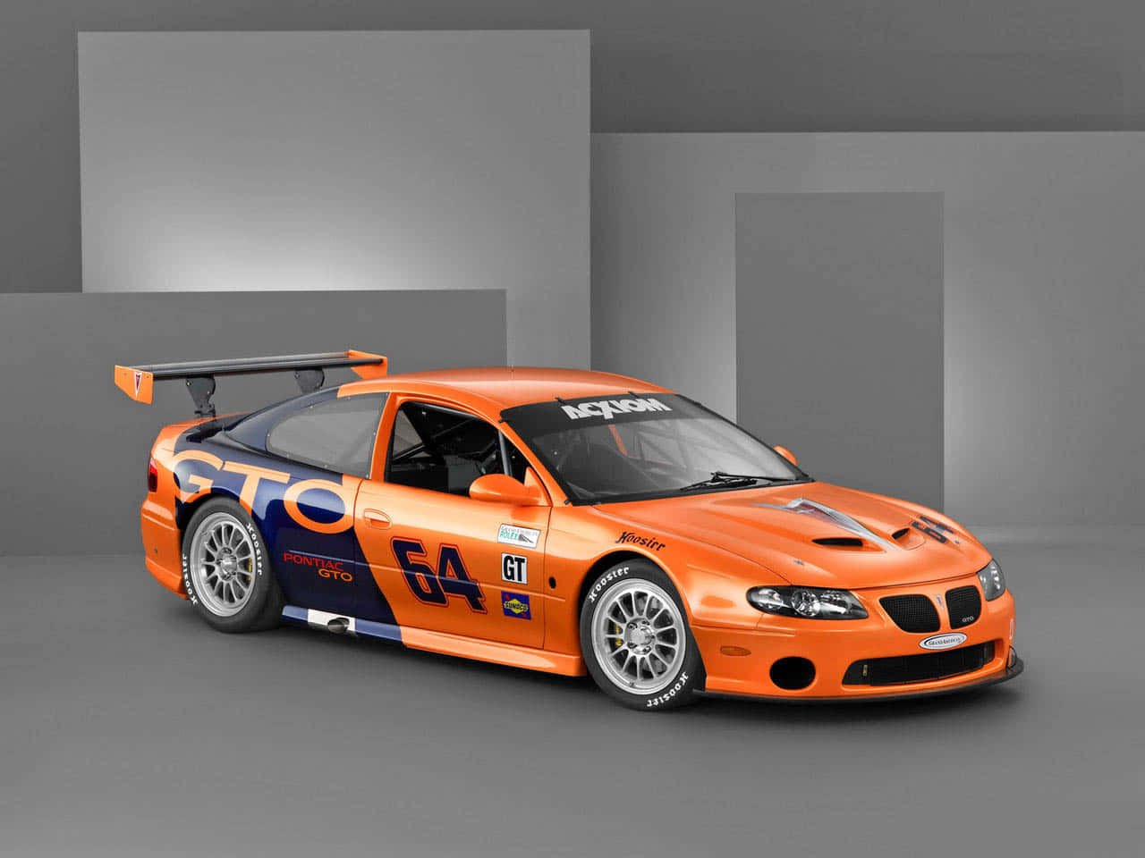 Car Racing 桌布 壁紙 — 一輛充滿活力的橙色Pontiac GTO賽車，帶有64號和贊助商貼紙，在簡約的灰色工作室環境中展示。