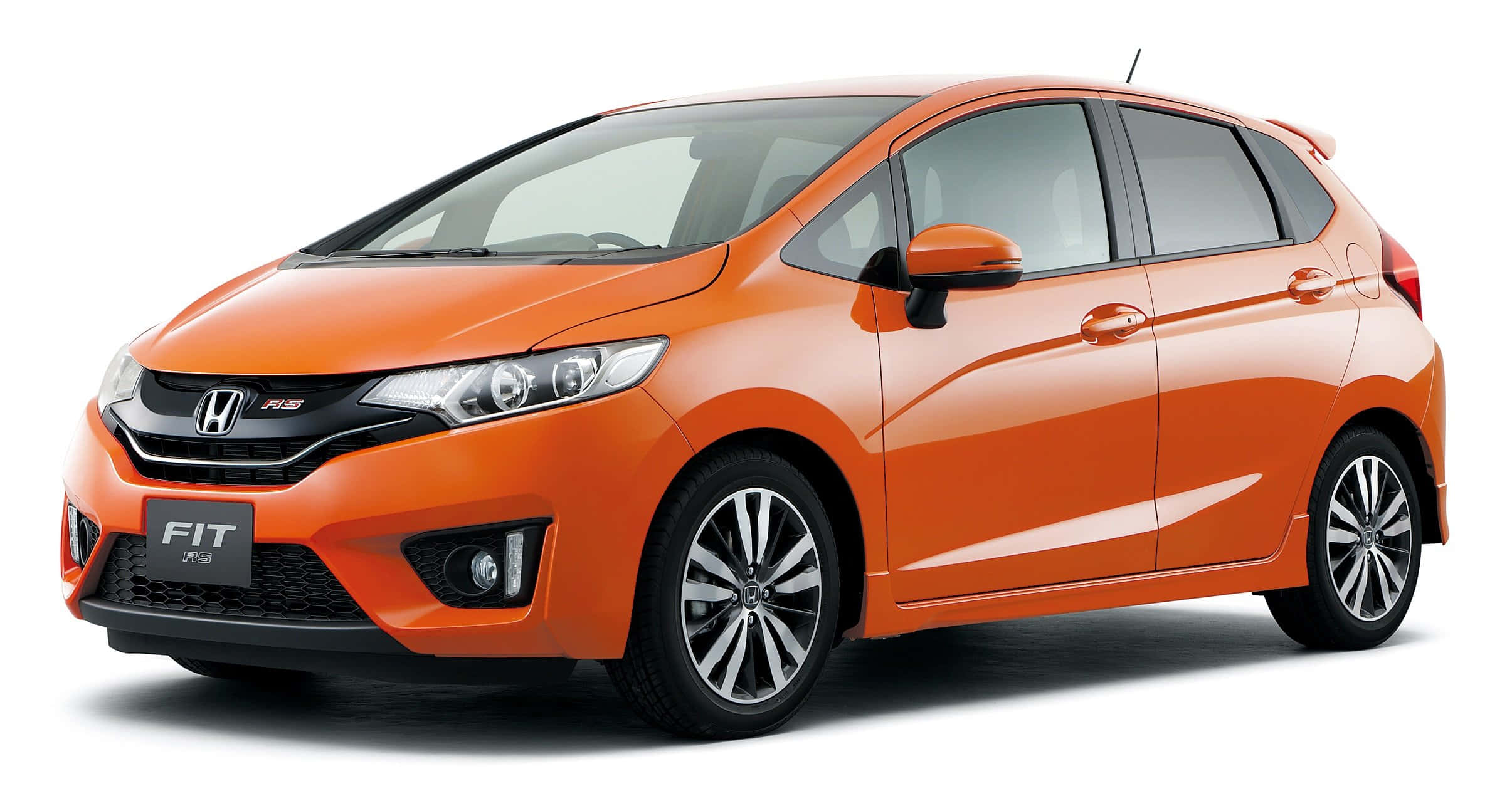 Honda Fit 桌布 壁紙 — 一輛充滿活力的橙色本田飛度掀背車在乾淨的白色背景下，在攝影棚燈光下閃閃發光。