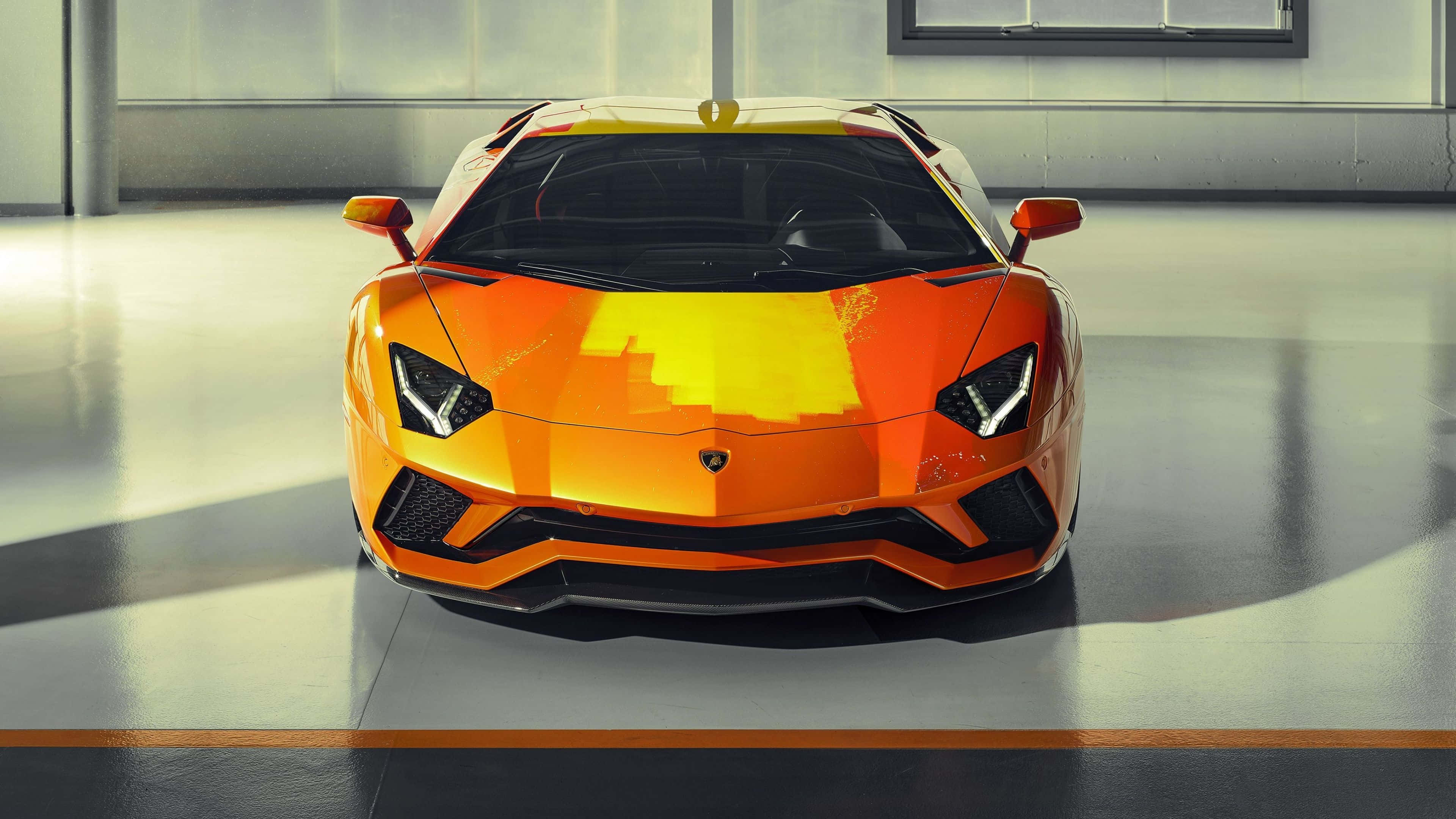 林寶堅尼 4K 桌布 壁紙 — 一輛充滿活力的橙色林寶堅尼Aventador，帶有像素化黃色點綴，在簡約車庫中正面朝前，處於明亮的攝影棚燈光下。